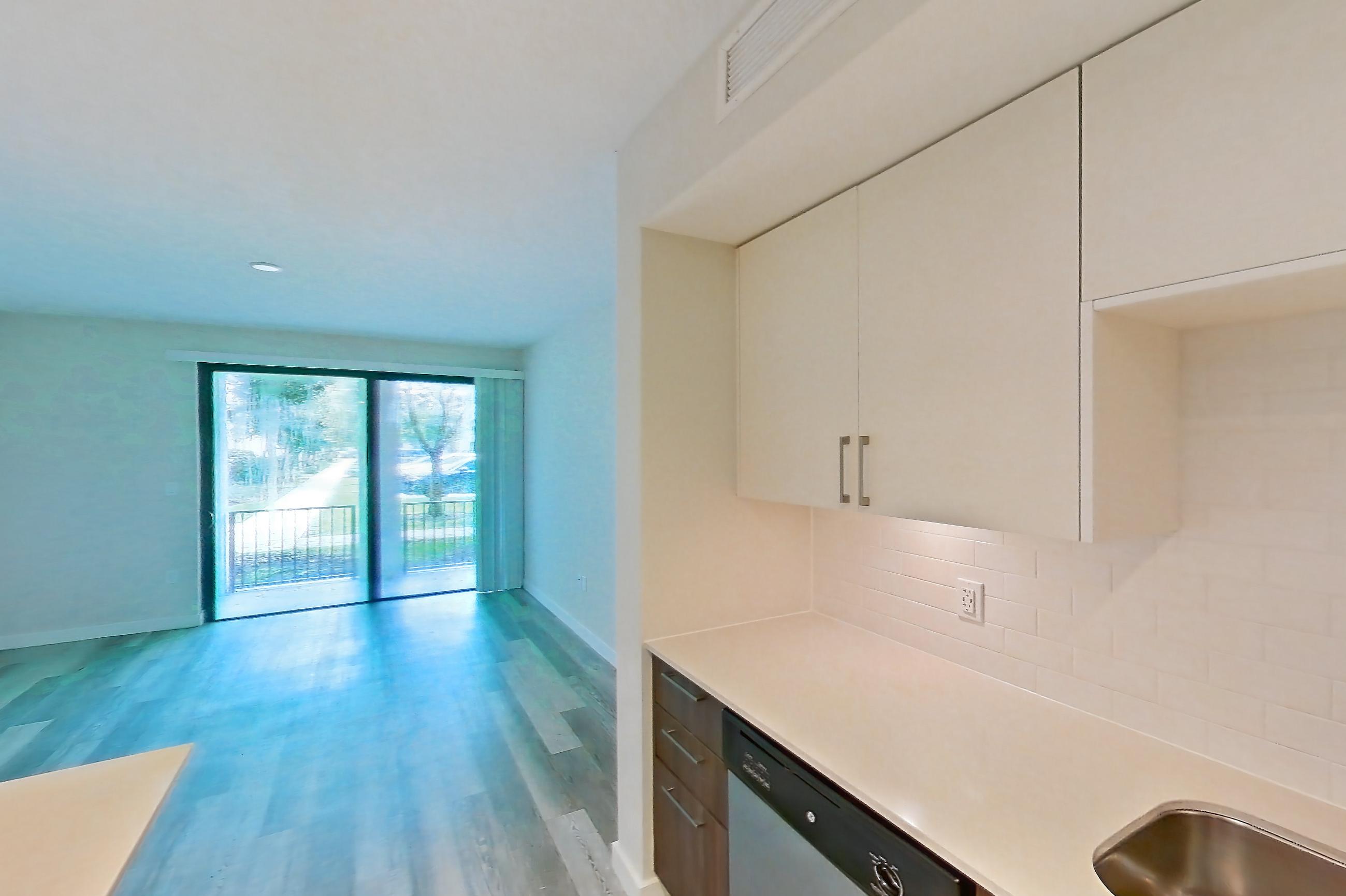 Kitchen with dishwasher, electric range, light countertops, light stone countertops, light wood-finish flooring, microwave, oven/range, refrigerator, and stainless steel appliances, Apartment 04-106 at Cortland South Kendall