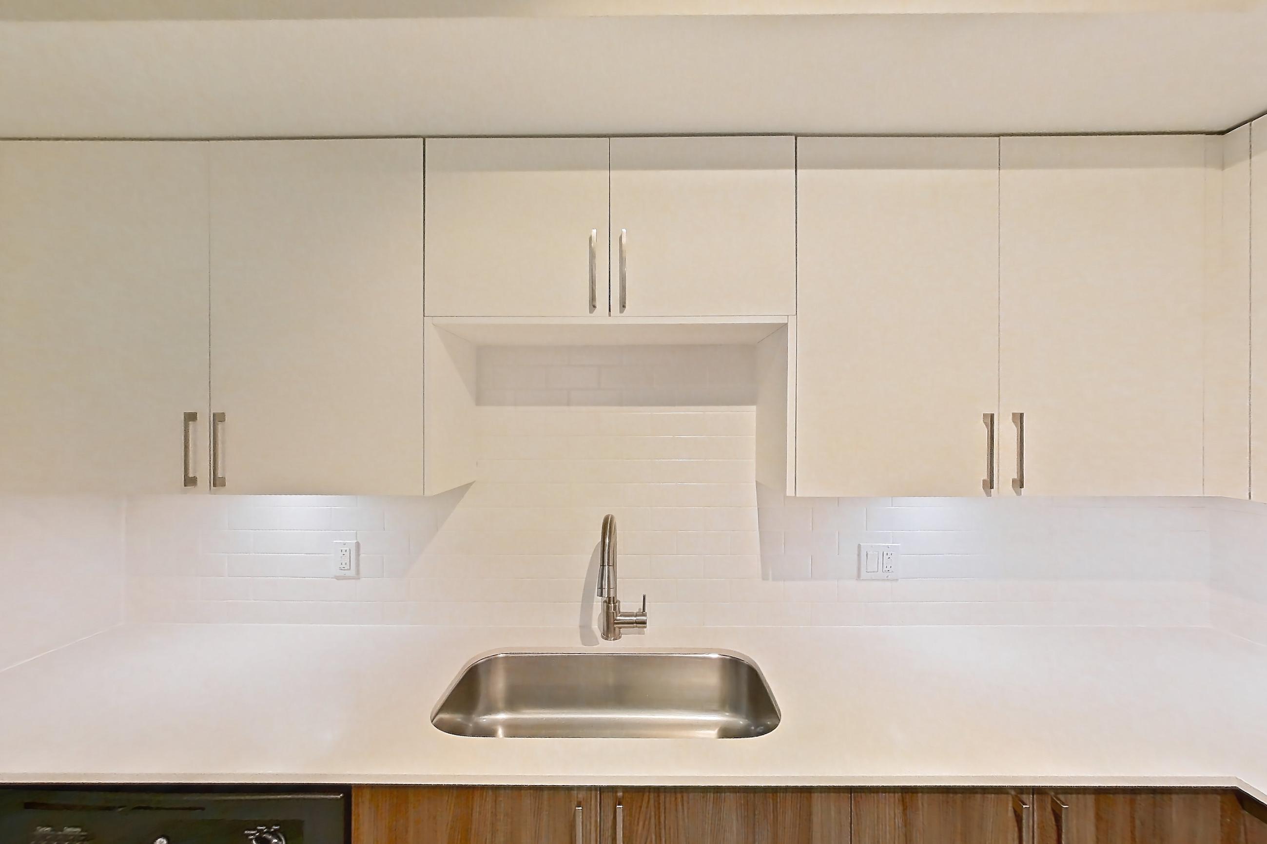 Kitchen with dishwasher, electric range, light countertops, light stone countertops, light wood-finish flooring, microwave, oven/range, refrigerator, and stainless steel appliances, Apartment 09-107 at Cortland South Kendall