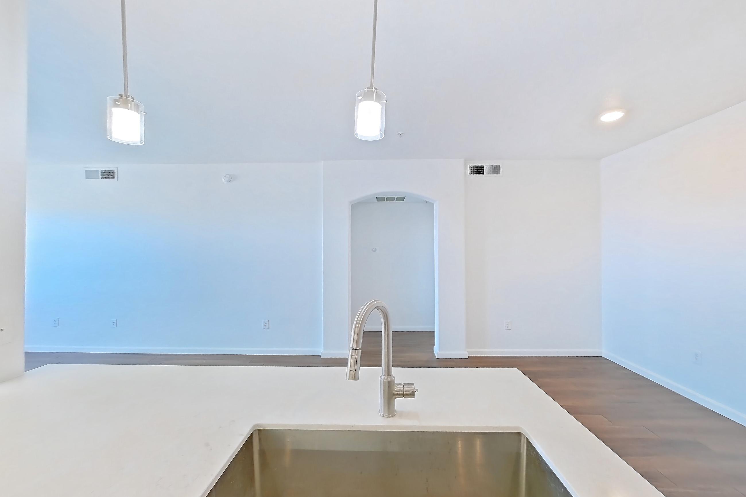 Kitchen with dark wood-finish flooring, dishwasher, electric range, light countertops, light stone countertops, light wood-finish flooring, microwave, oven/range, and stainless steel appliances, Apartment 3091 at Cortland South Mountain