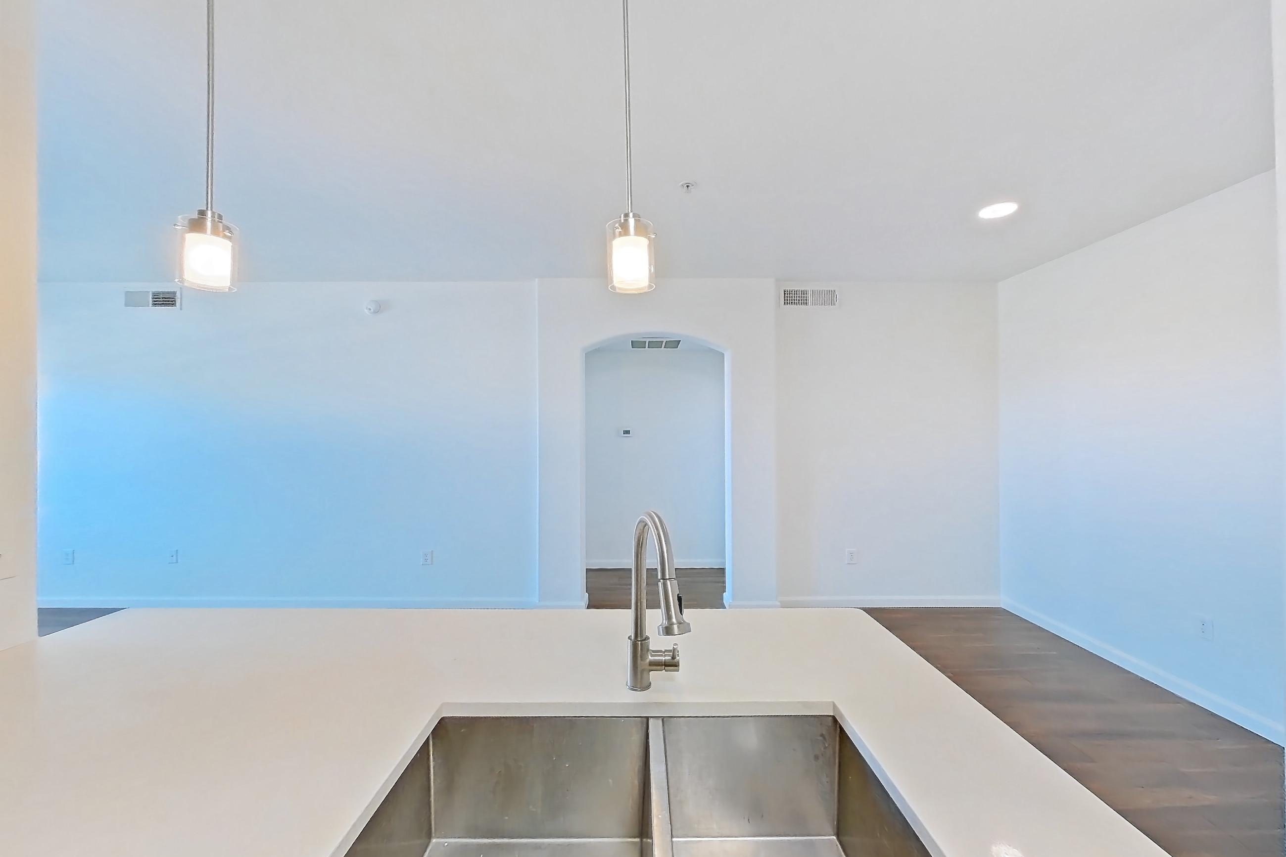 Kitchen with dark wood-finish flooring, dishwasher, electric range, kitchen island, light countertops, light stone countertops, light wood-finish flooring, microwave, oven/range, and stainless steel appliances, Apartment 3101 at Cortland South Mountain