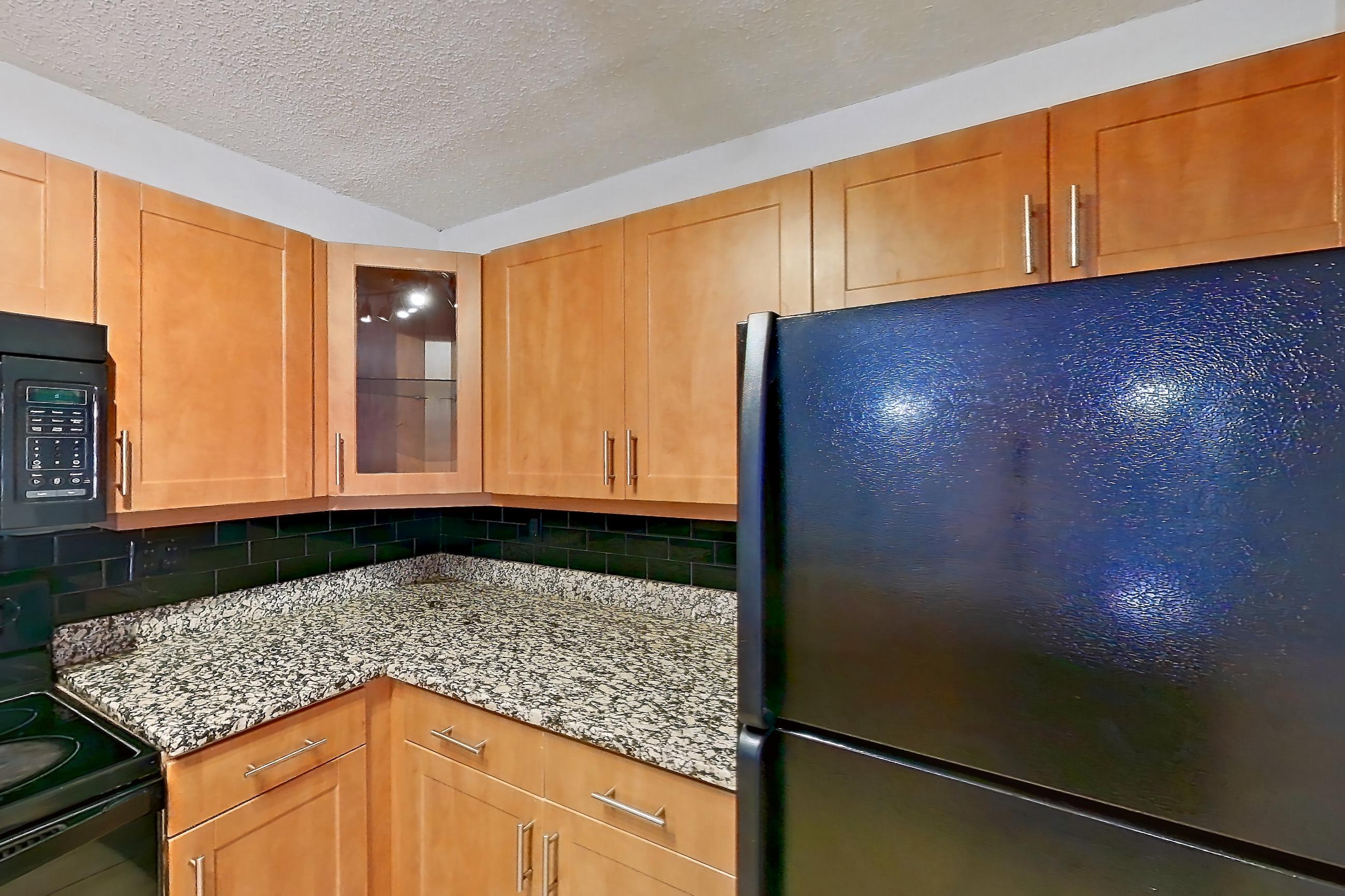 Kitchen with black appliances, dishwasher, electric range, light stone countertops, light tile flooring, microwave, oven/range, and refrigerator, Apartment 455465 at Cortland Bayport
