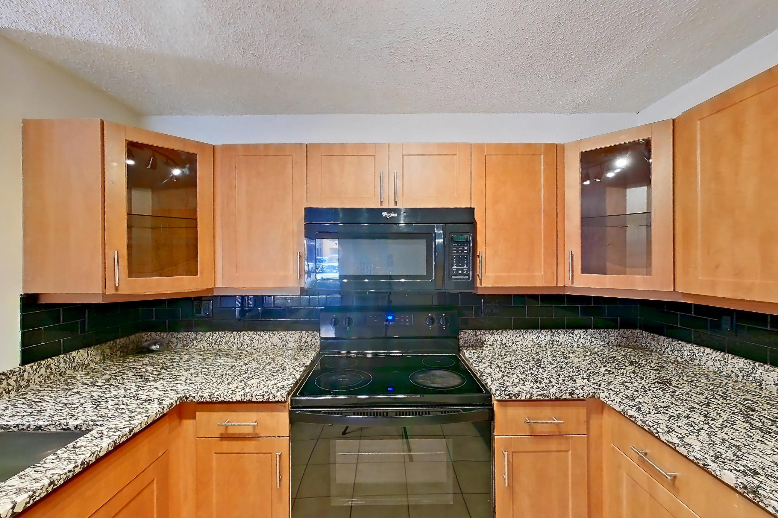 Kitchen with black appliances, dishwasher, electric range, light stone countertops, light tile flooring, microwave, oven/range, and refrigerator, Apartment 455465 at Cortland Bayport