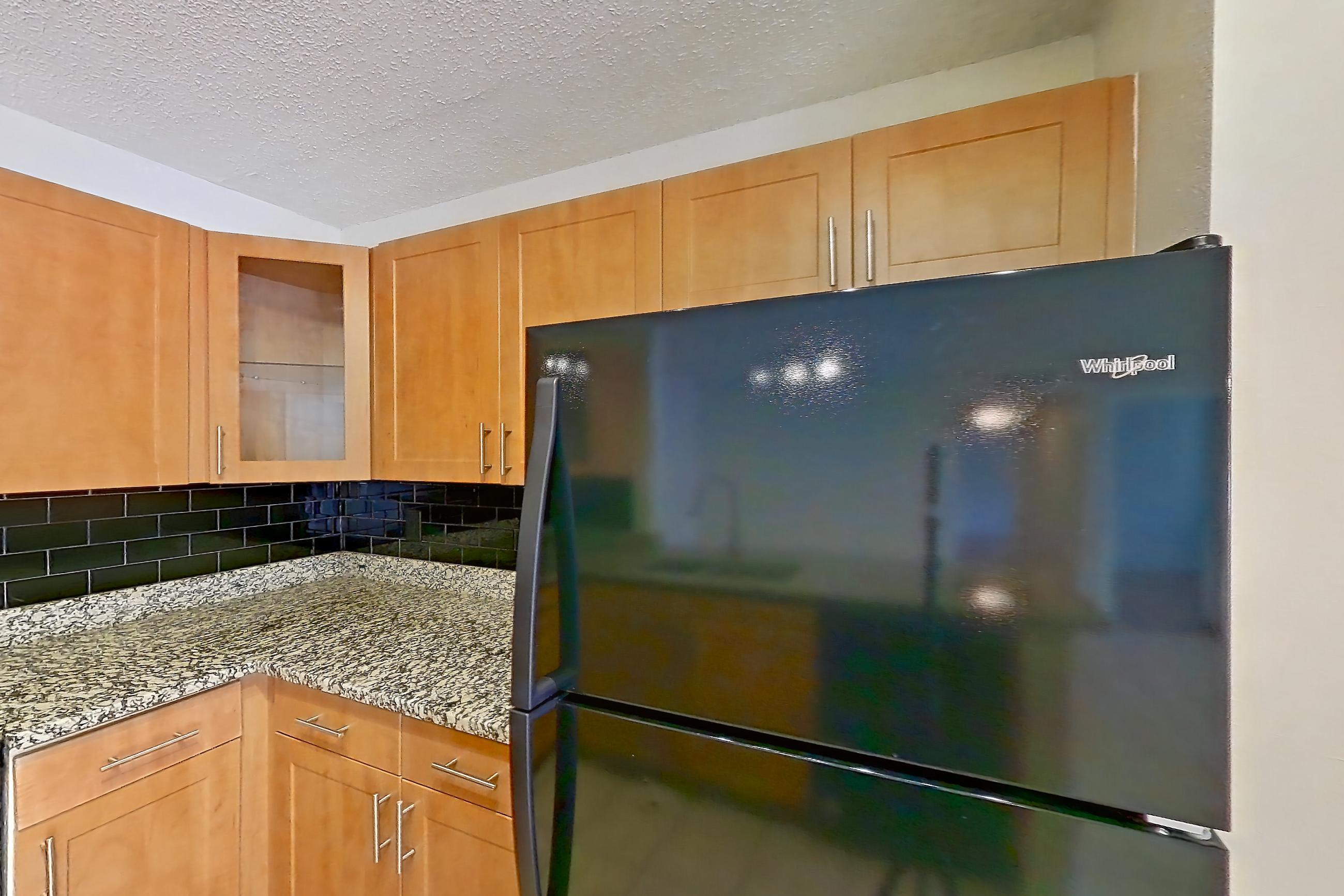 Kitchen with black appliances, dishwasher, electric range, light stone countertops, light tile flooring, microwave, oven/range, and refrigerator, Apartment 465442 at Cortland Bayport