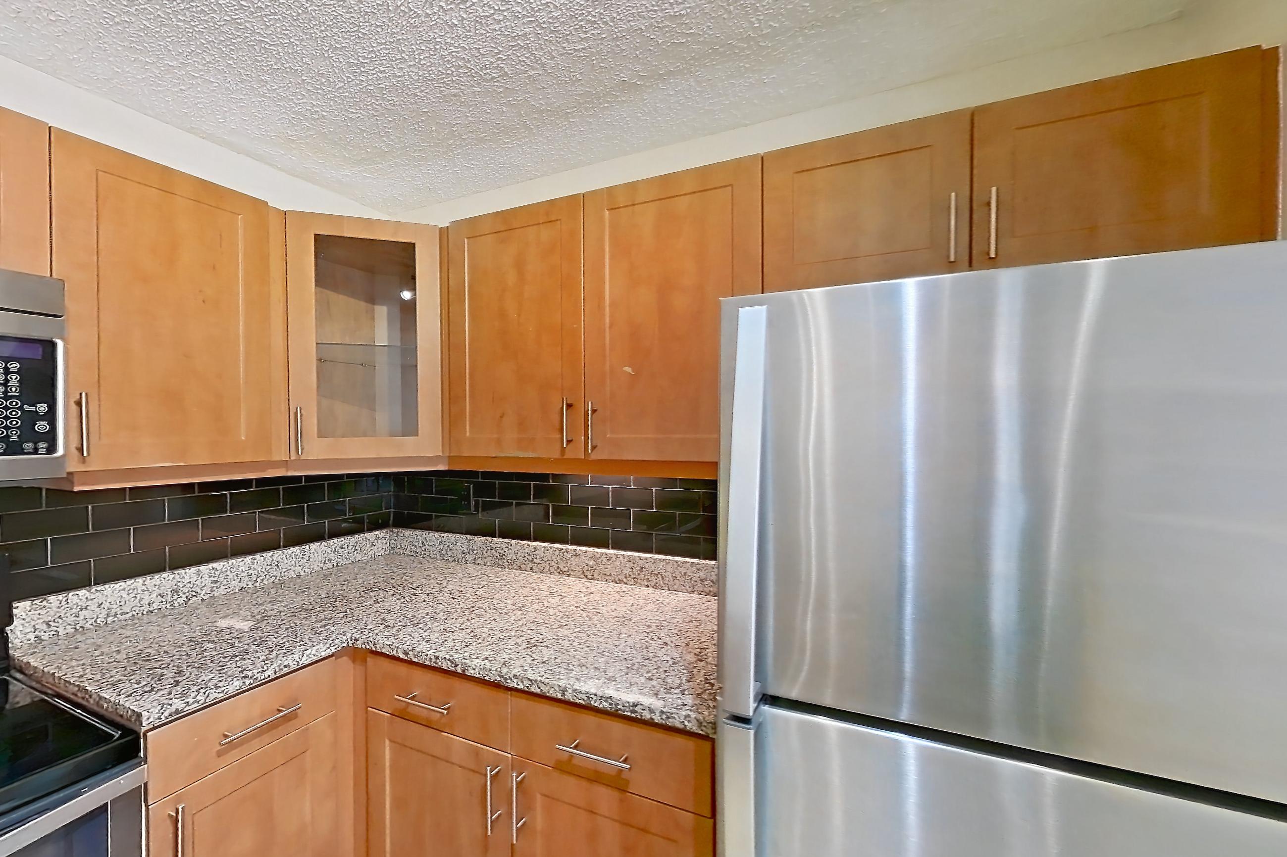 Kitchen with black appliances, dishwasher, electric range, light stone countertops, light tile flooring, microwave, oven/range, refrigerator, and stainless steel appliances, Apartment 475441 at Cortland Bayport