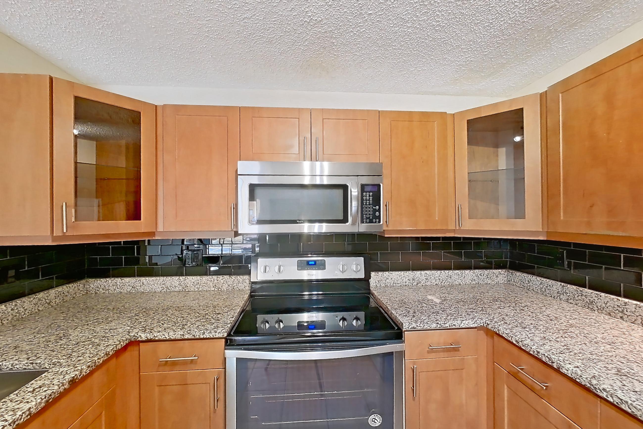 Kitchen with black appliances, dishwasher, electric range, light stone countertops, light tile flooring, microwave, oven/range, refrigerator, and stainless steel appliances, Apartment 475441 at Cortland Bayport