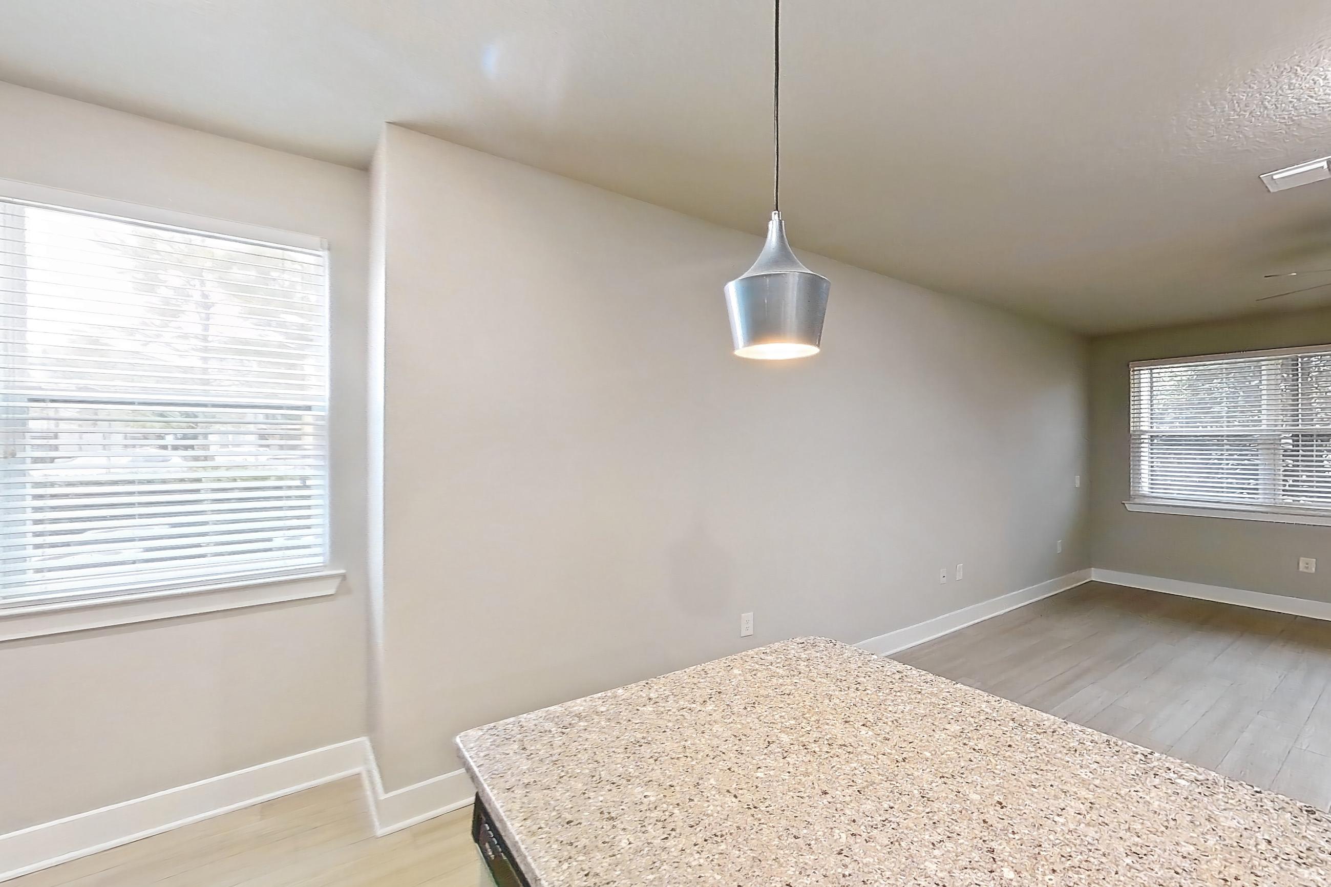Kitchen with dishwasher, kitchen island, light countertops, light stone countertops, light wood-finish flooring, oven/range, refrigerator, and stainless steel appliances, Apartment 17A-103 at Cortland Reunion