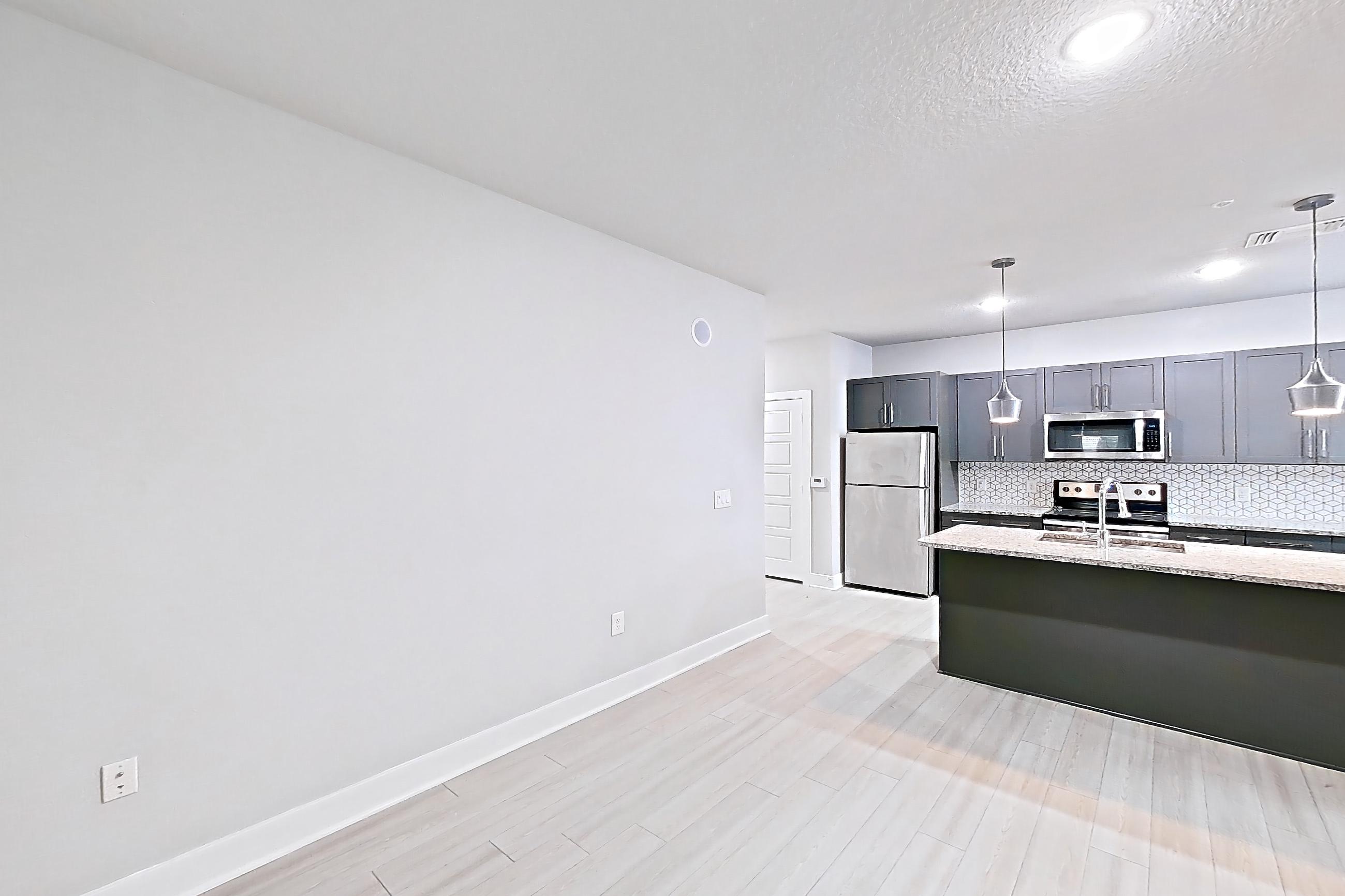Living room with electric range, light stone countertops, light wood-finish flooring, oven/range, refrigerator, and stainless steel appliances, Apartment 17A-103 at Cortland Reunion