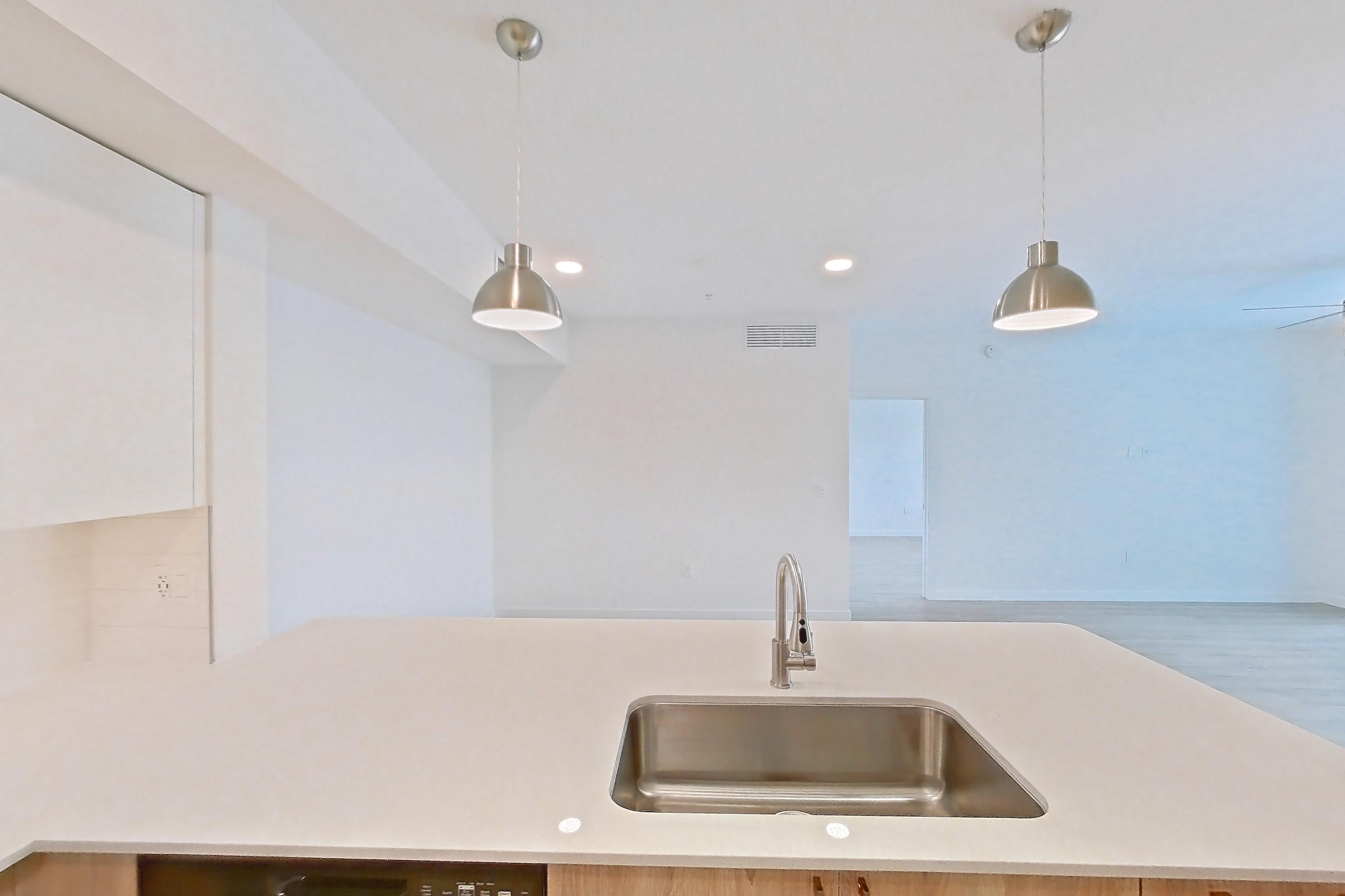 Kitchen with dishwasher, electric range, light countertops, light stone countertops, light wood-finish flooring, microwave, oven/range, refrigerator, and stainless steel appliances, Apartment 26-305 at Cortland South Kendall