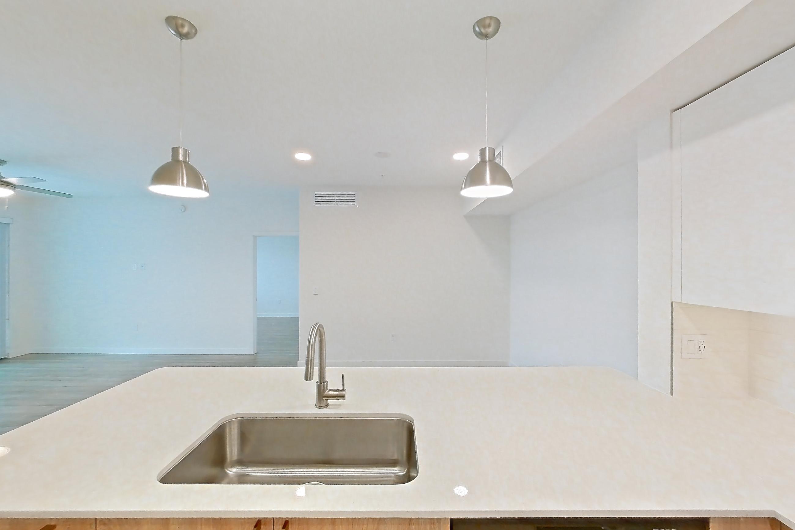 Kitchen with dishwasher, electric range, light countertops, light stone countertops, light wood-finish flooring, microwave, oven/range, refrigerator, and stainless steel appliances, Apartment 26-306 at Cortland South Kendall