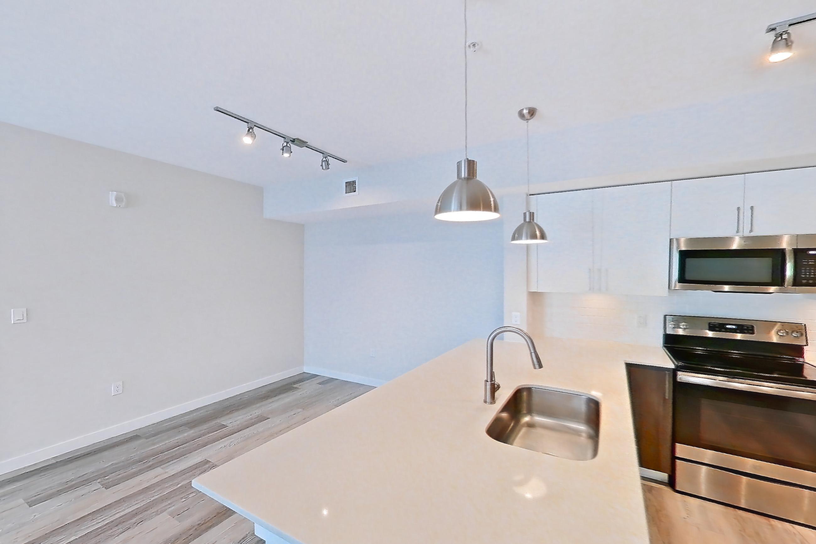 Kitchen entryway with electric range, light countertops, light stone countertops, light wood-finish flooring, oven/range, refrigerator, and stainless steel appliances, Apartment 02-303 at Cortland South Kendall