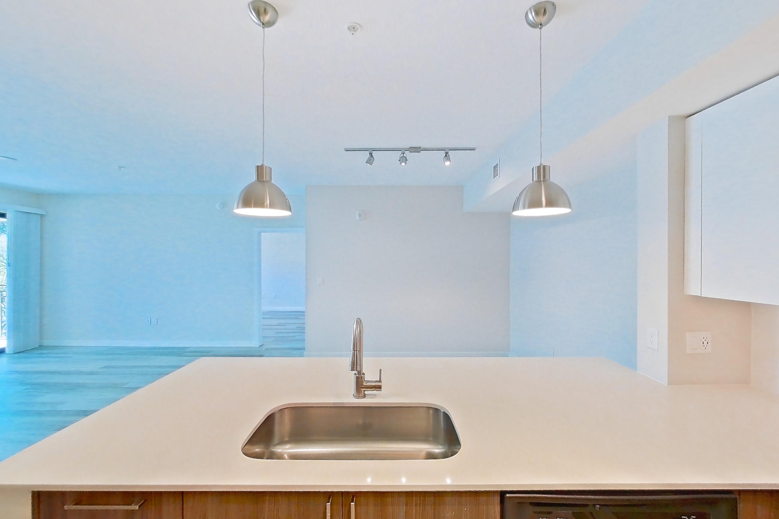 Kitchen with dishwasher, electric range, light countertops, light stone countertops, light wood-finish flooring, microwave, oven/range, range hood, refrigerator, and stainless steel appliances, Apartment 02-303 at Cortland South Kendall