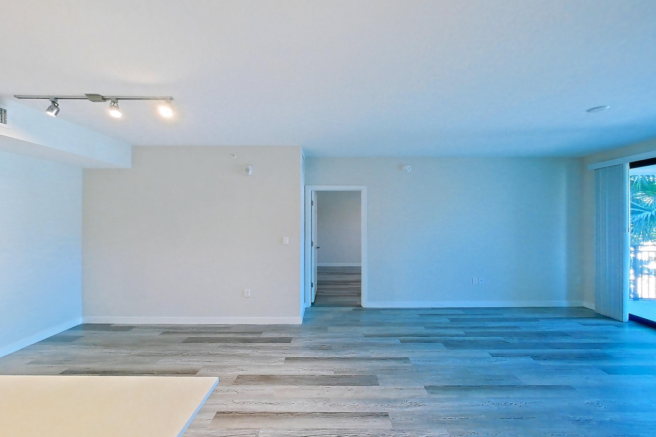 Kitchen entryway with electric range, light countertops, light stone countertops, light wood-finish flooring, oven/range, refrigerator, and stainless steel appliances, Apartment 05-204 at Cortland South Kendall