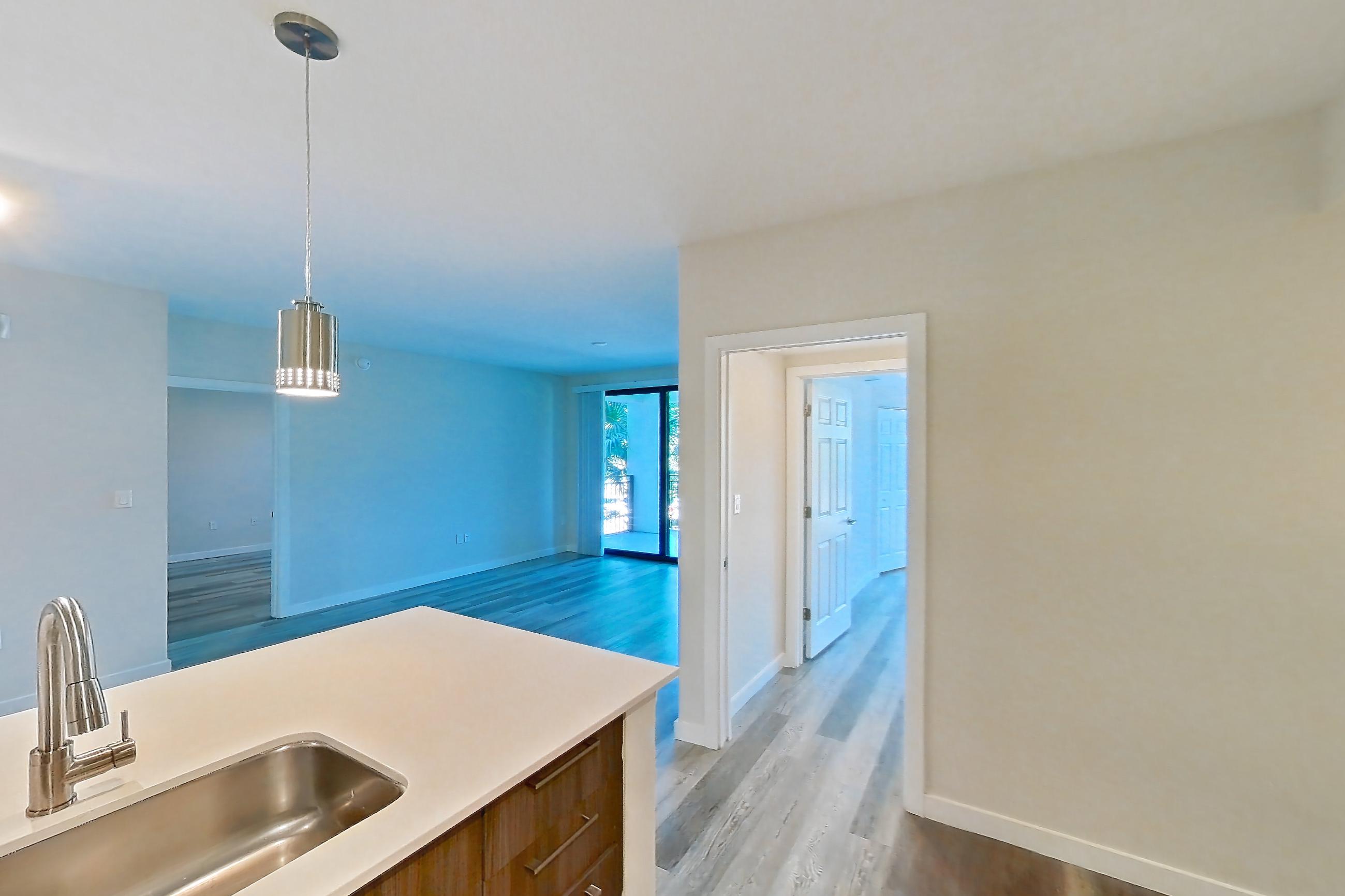 Kitchen with dishwasher, electric range, light countertops, light stone countertops, light wood-finish flooring, microwave, oven/range, refrigerator, and stainless steel appliances, Apartment 05-204 at Cortland South Kendall