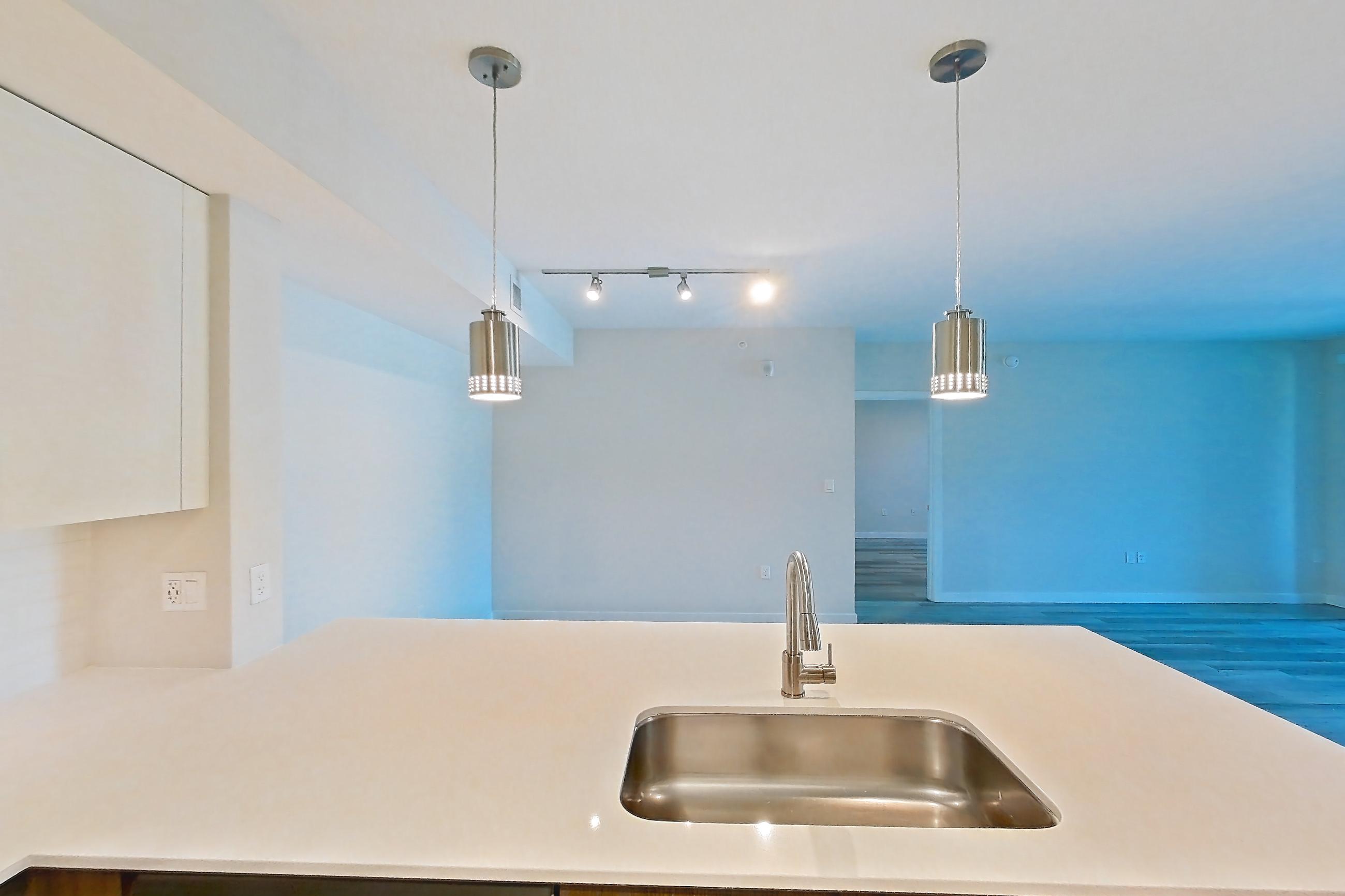 Kitchen with dishwasher, electric range, light countertops, light stone countertops, light wood-finish flooring, microwave, oven/range, refrigerator, and stainless steel appliances, Apartment 05-204 at Cortland South Kendall
