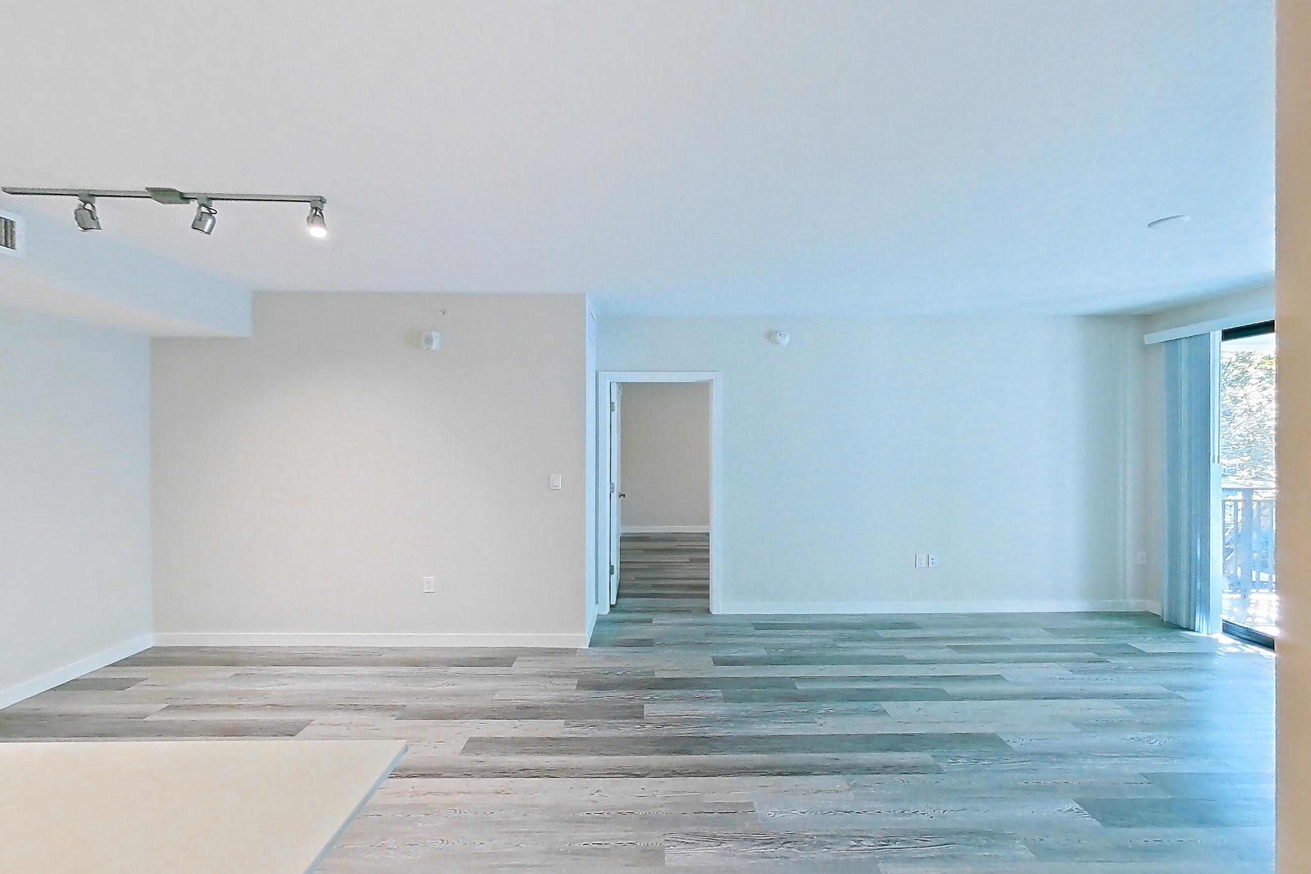 Kitchen entryway with electric range, light countertops, light stone countertops, light wood-finish flooring, oven/range, refrigerator, and stainless steel appliances, Apartment 05-205 at Cortland South Kendall