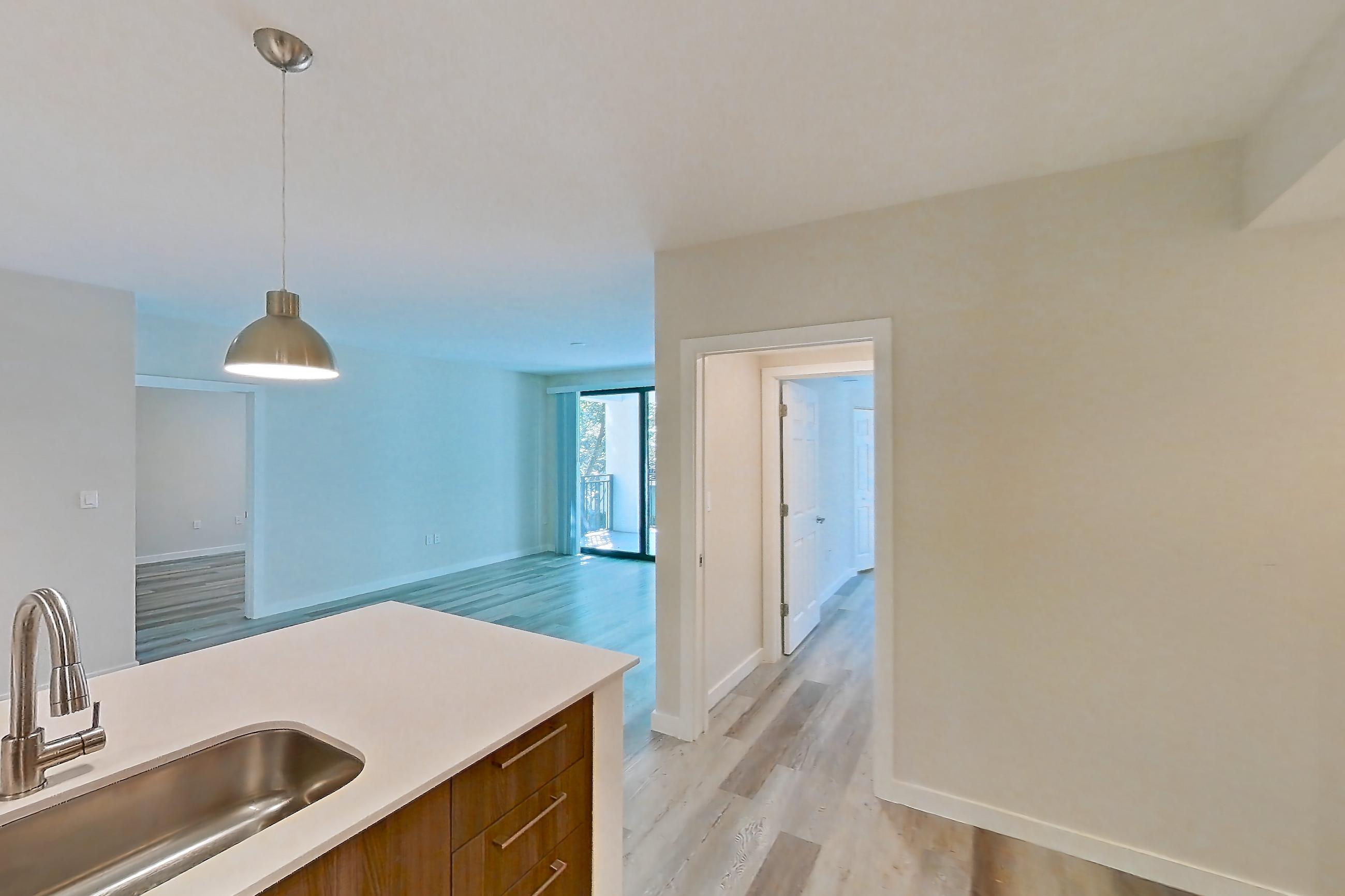 Kitchen with dishwasher, electric range, light countertops, light stone countertops, light wood-finish flooring, microwave, oven/range, refrigerator, and stainless steel appliances, Apartment 05-205 at Cortland South Kendall