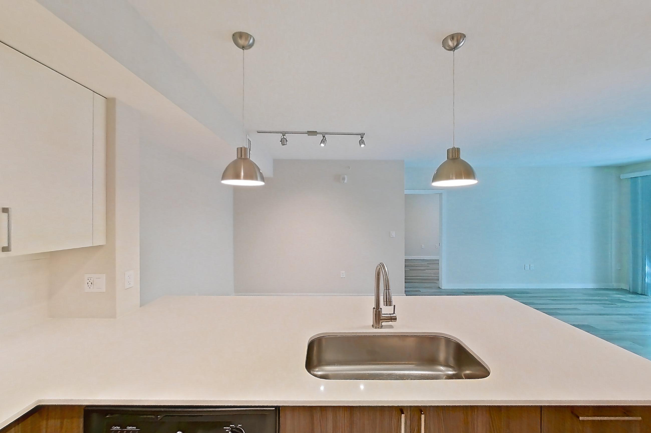Kitchen with dishwasher, electric range, light countertops, light stone countertops, light wood-finish flooring, microwave, oven/range, refrigerator, and stainless steel appliances, Apartment 05-205 at Cortland South Kendall