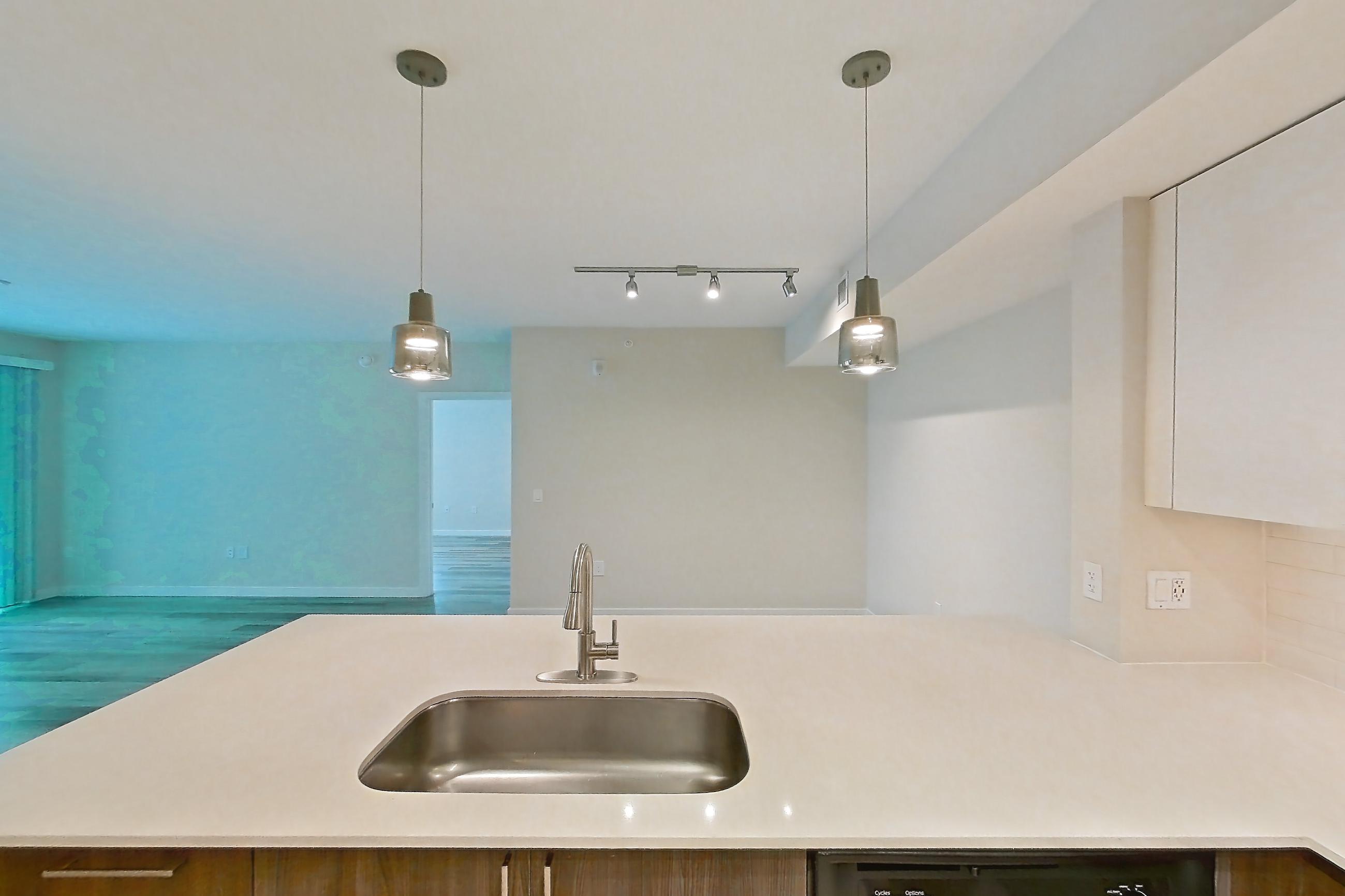 Kitchen with dishwasher, electric range, light countertops, light stone countertops, light wood-finish flooring, microwave, oven/range, range hood, refrigerator, and stainless steel appliances, Apartment 06-102 at Cortland South Kendall