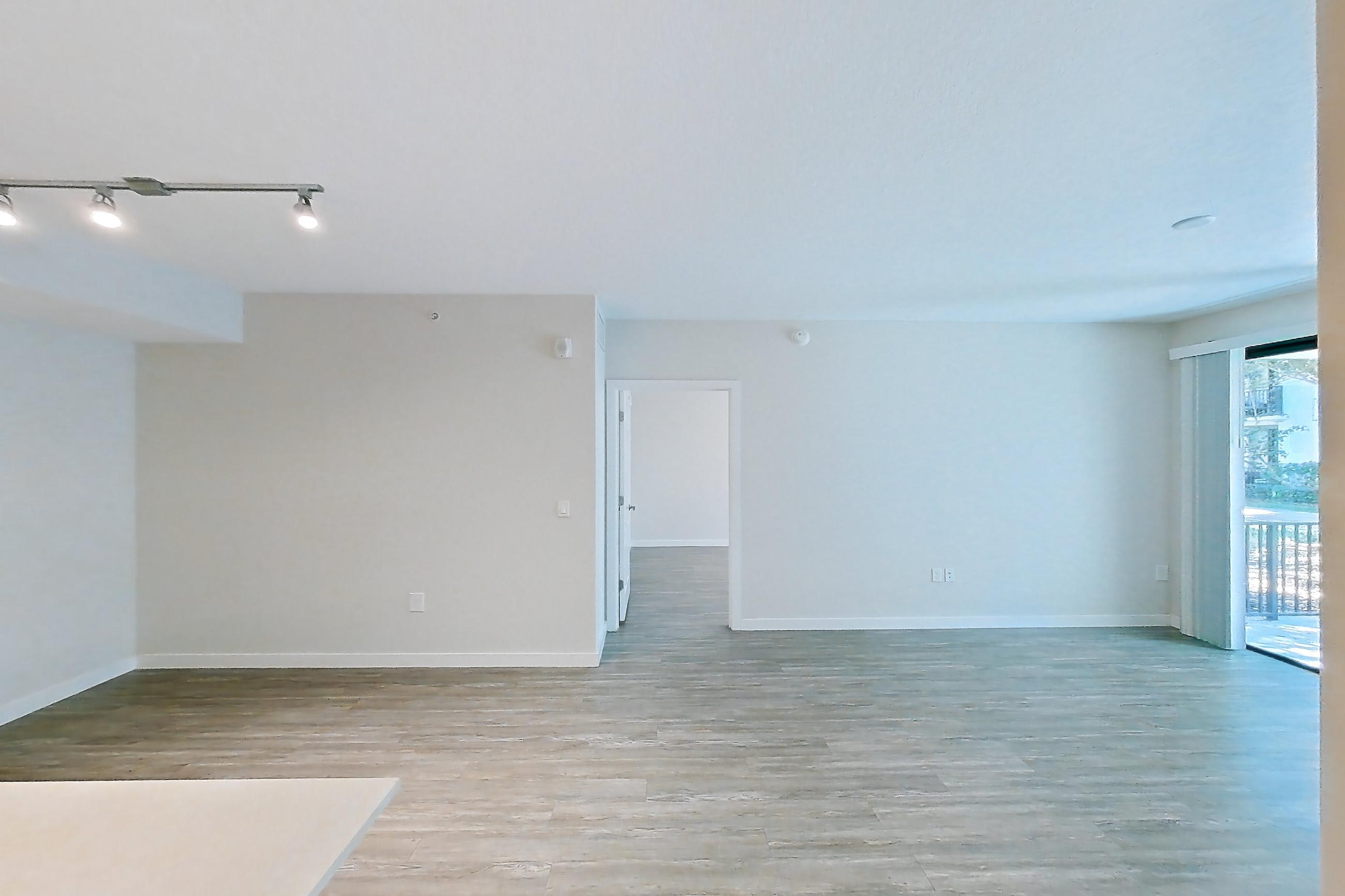 Kitchen entryway with electric range, light countertops, light stone countertops, light wood-finish flooring, oven/range, refrigerator, and stainless steel appliances, Apartment 10-101 at Cortland South Kendall