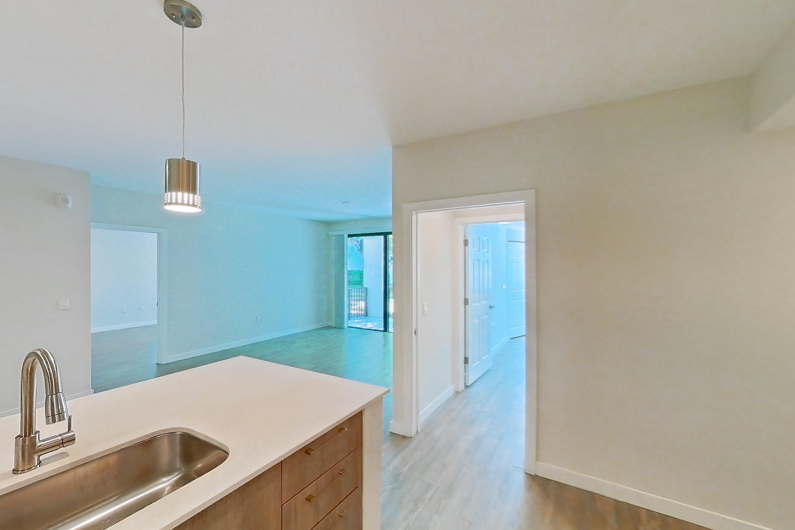 Kitchen with dishwasher, electric range, light countertops, light stone countertops, light wood-finish flooring, microwave, oven/range, refrigerator, and stainless steel appliances, Apartment 10-101 at Cortland South Kendall