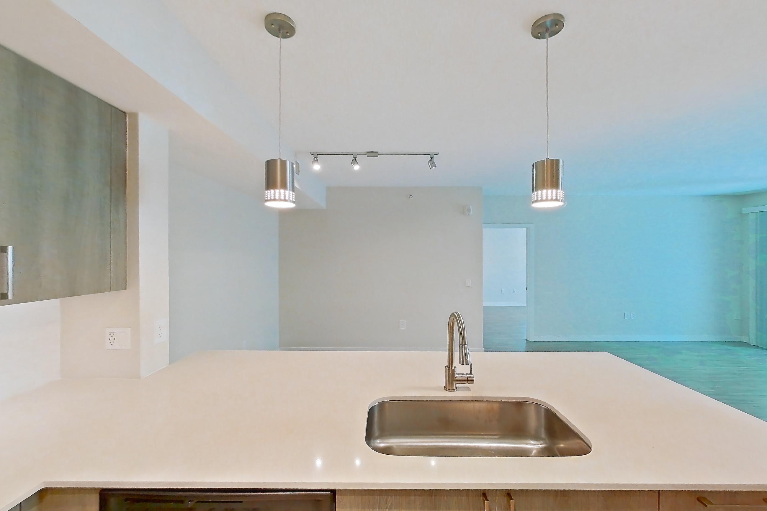 Kitchen with dishwasher, electric range, light countertops, light stone countertops, light wood-finish flooring, microwave, oven/range, refrigerator, and stainless steel appliances, Apartment 10-101 at Cortland South Kendall