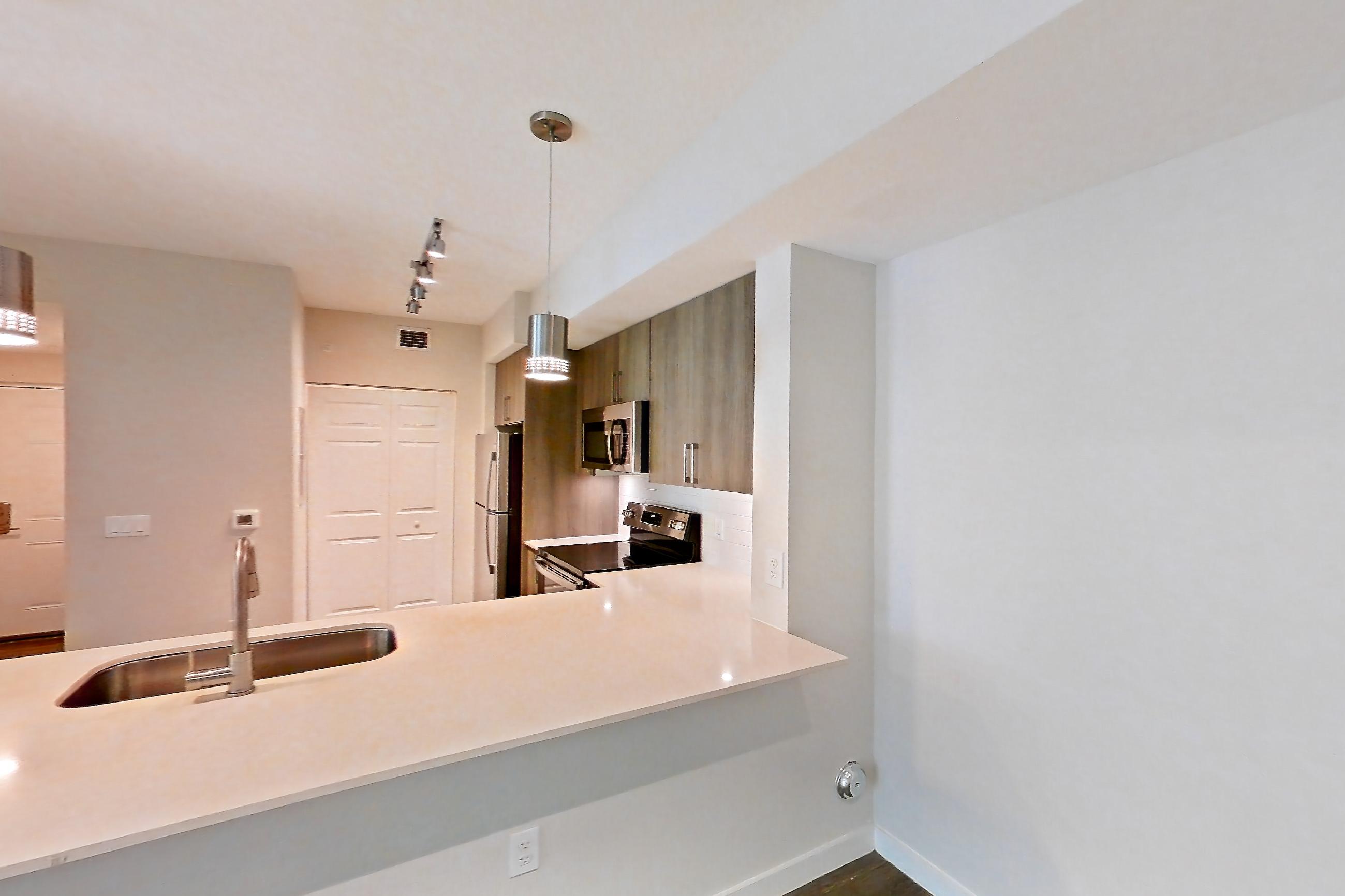 Living space with electric range, light stone countertops, light wood-finish flooring, oven/range, refrigerator, stainless steel appliances, and white appliances, Apartment 10-101 at Cortland South Kendall