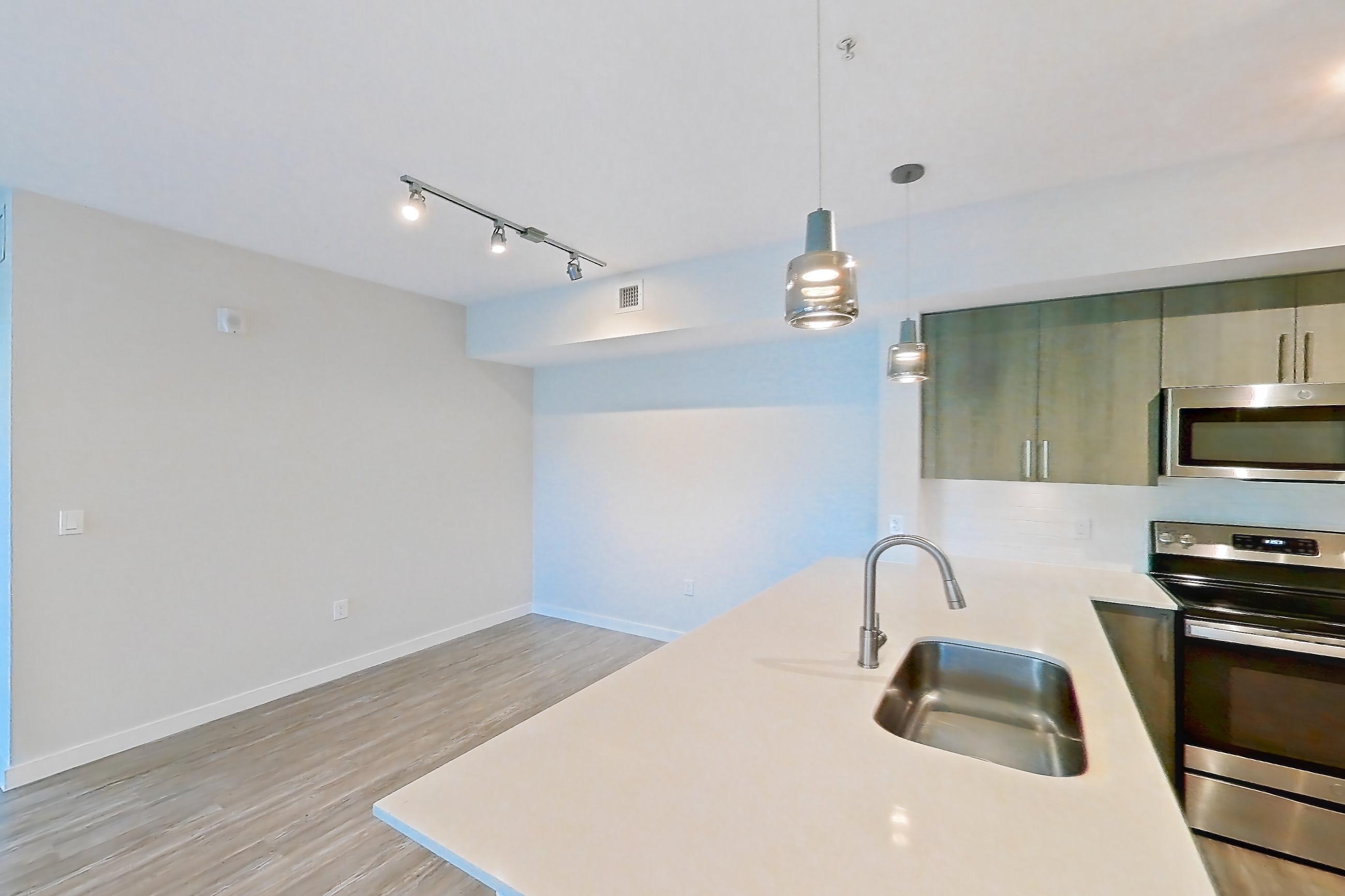 Kitchen entryway with electric range, light stone countertops, light wood-finish flooring, oven/range, refrigerator, and stainless steel appliances, Apartment 11-307 at Cortland South Kendall