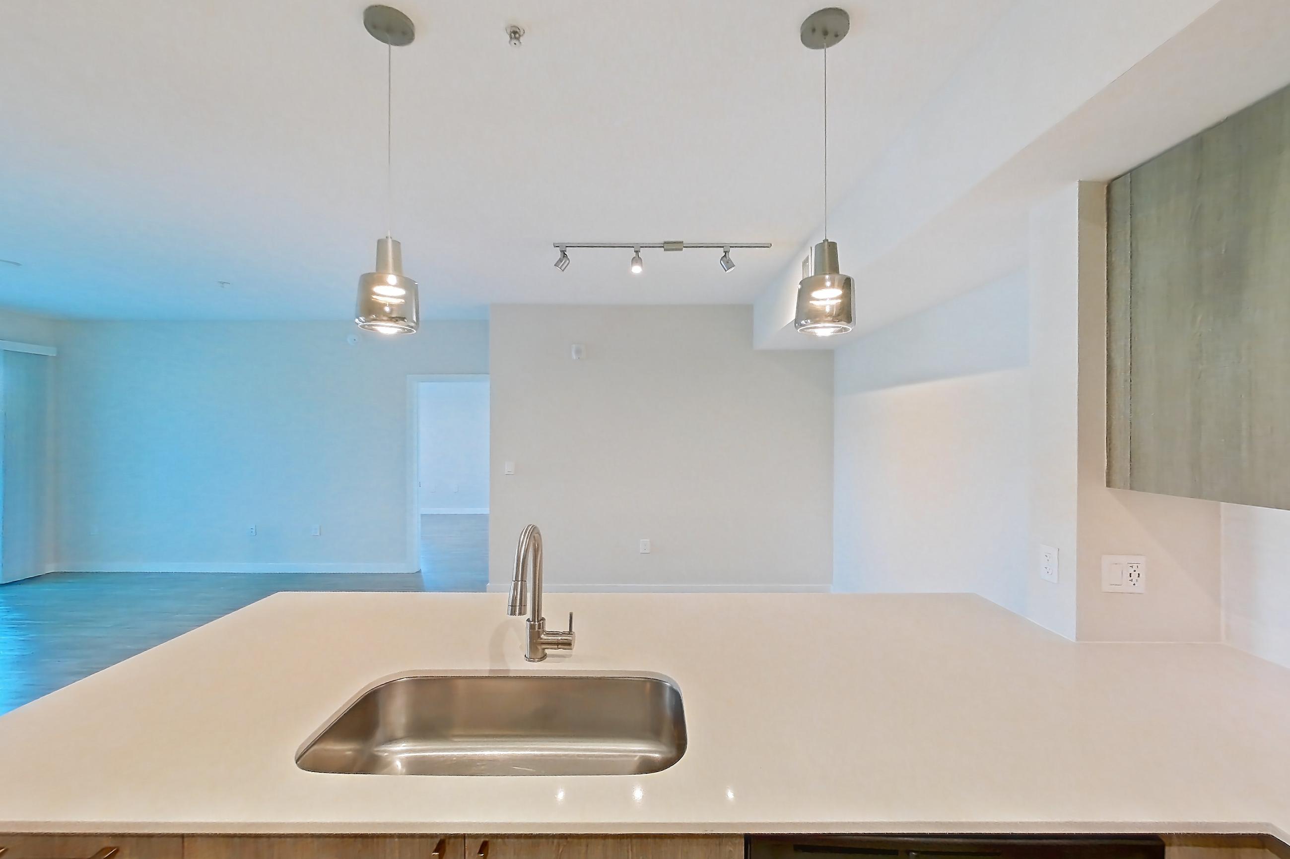 Kitchen with dishwasher, electric range, light countertops, light stone countertops, light wood-finish flooring, microwave, oven/range, refrigerator, and stainless steel appliances, Apartment 11-307 at Cortland South Kendall