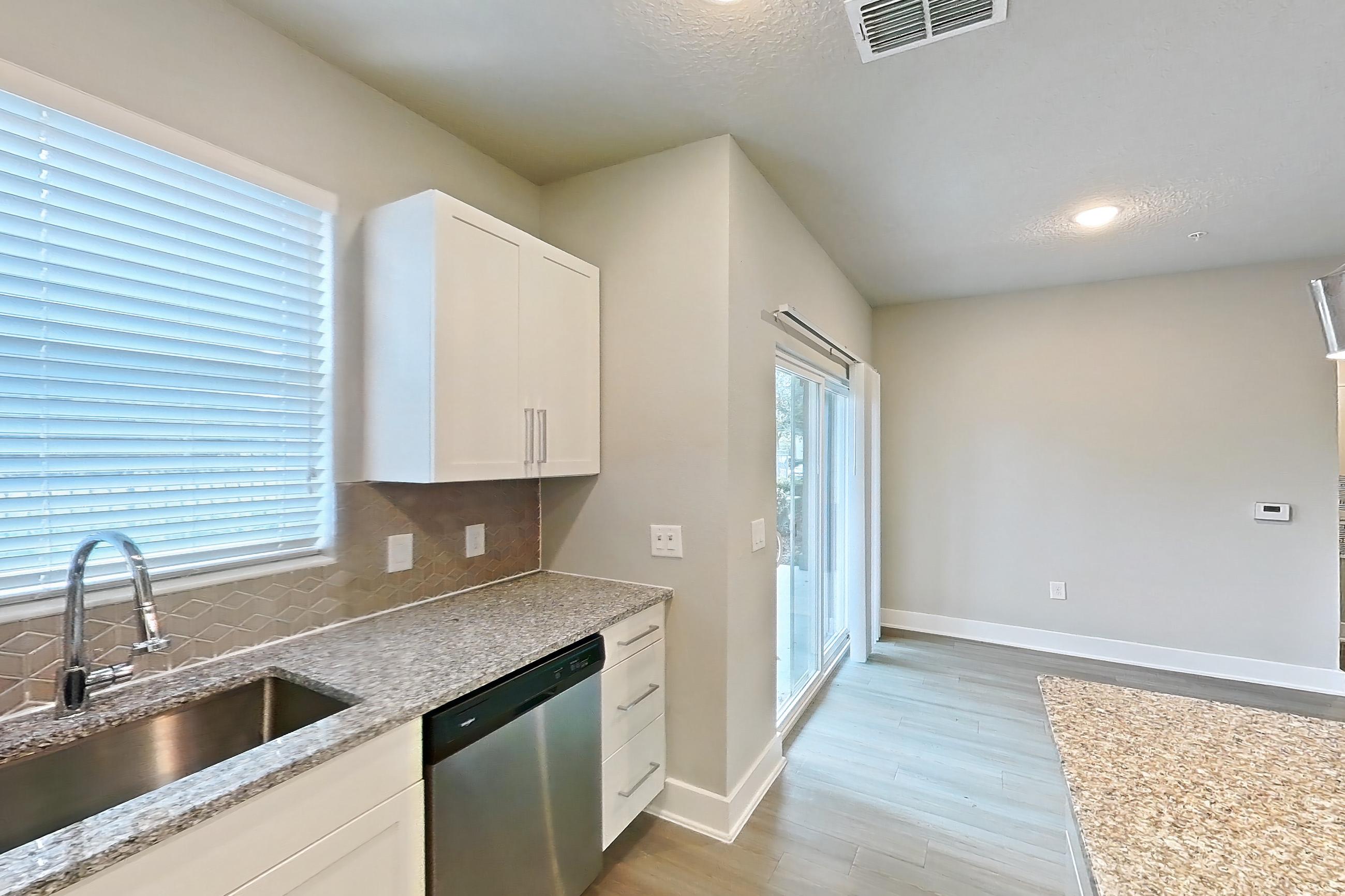 Kitchen with dark wood-finish flooring, dishwasher, electric range, light countertops, light stone countertops, light wood-finish flooring, oven/range, refrigerator, and stainless steel appliances, Apartment 04-186 at Cortland Reunion