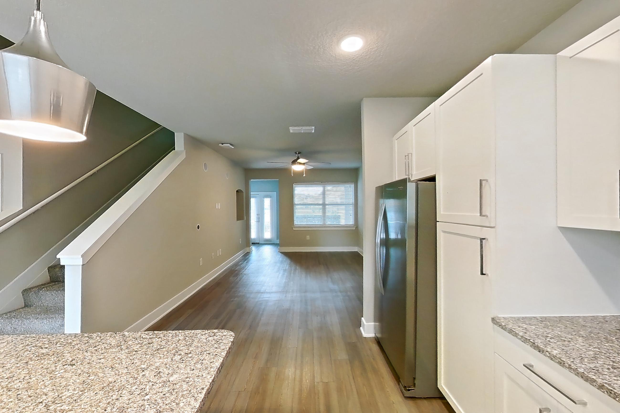 Kitchen with dark wood-finish flooring, dishwasher, electric range, light countertops, light stone countertops, light wood-finish flooring, oven/range, refrigerator, and stainless steel appliances, Apartment 04-186 at Cortland Reunion