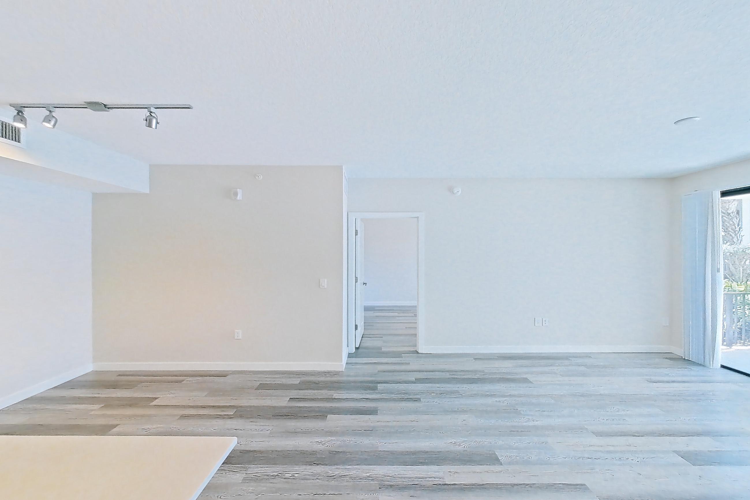 Kitchen entryway with electric range, light countertops, light stone countertops, light wood-finish flooring, oven/range, refrigerator, and stainless steel appliances, Apartment 15-108 at Cortland South Kendall