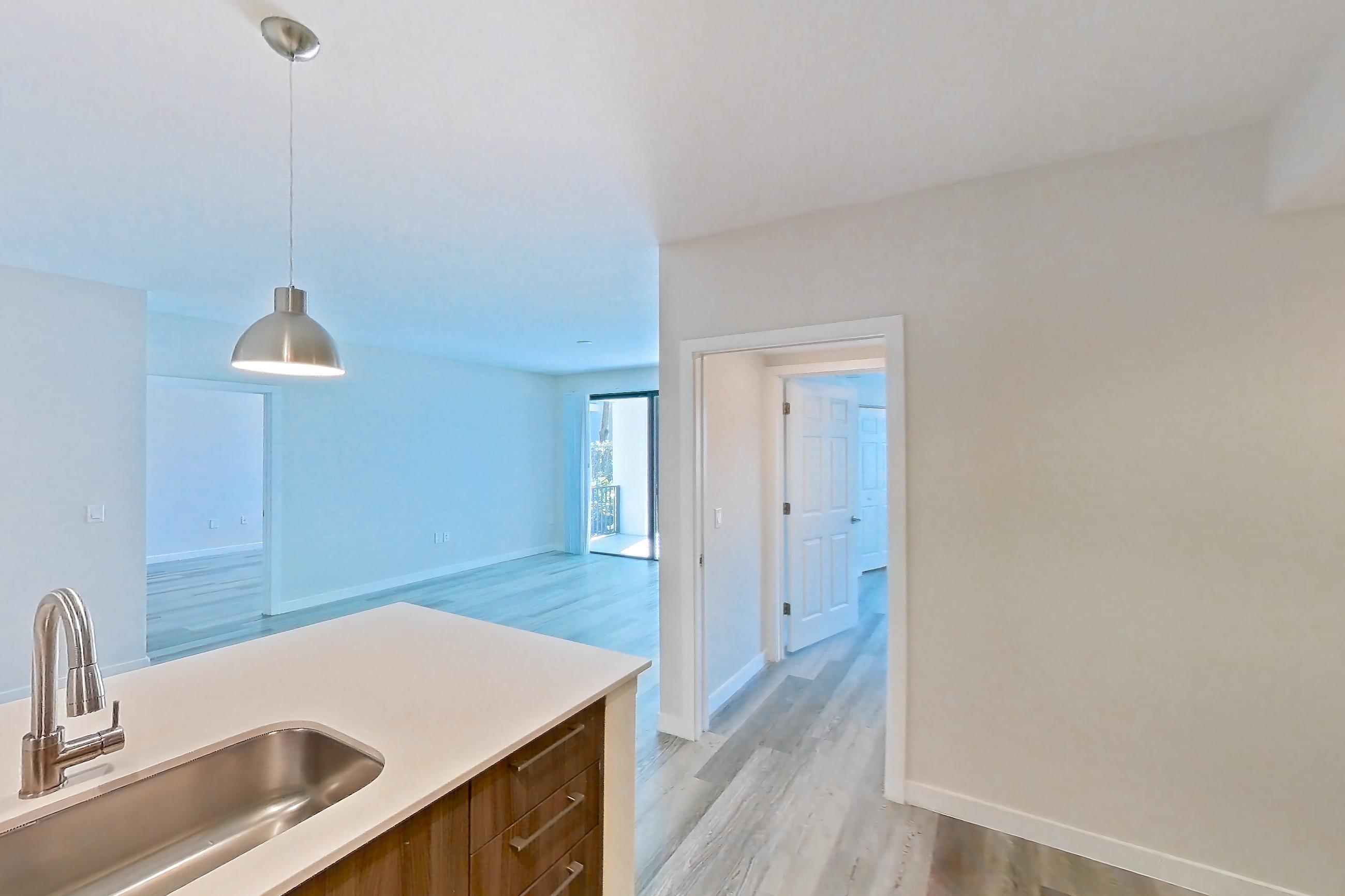 Kitchen with dishwasher, electric range, light countertops, light stone countertops, light wood-finish flooring, microwave, oven/range, refrigerator, and stainless steel appliances, Apartment 15-108 at Cortland South Kendall