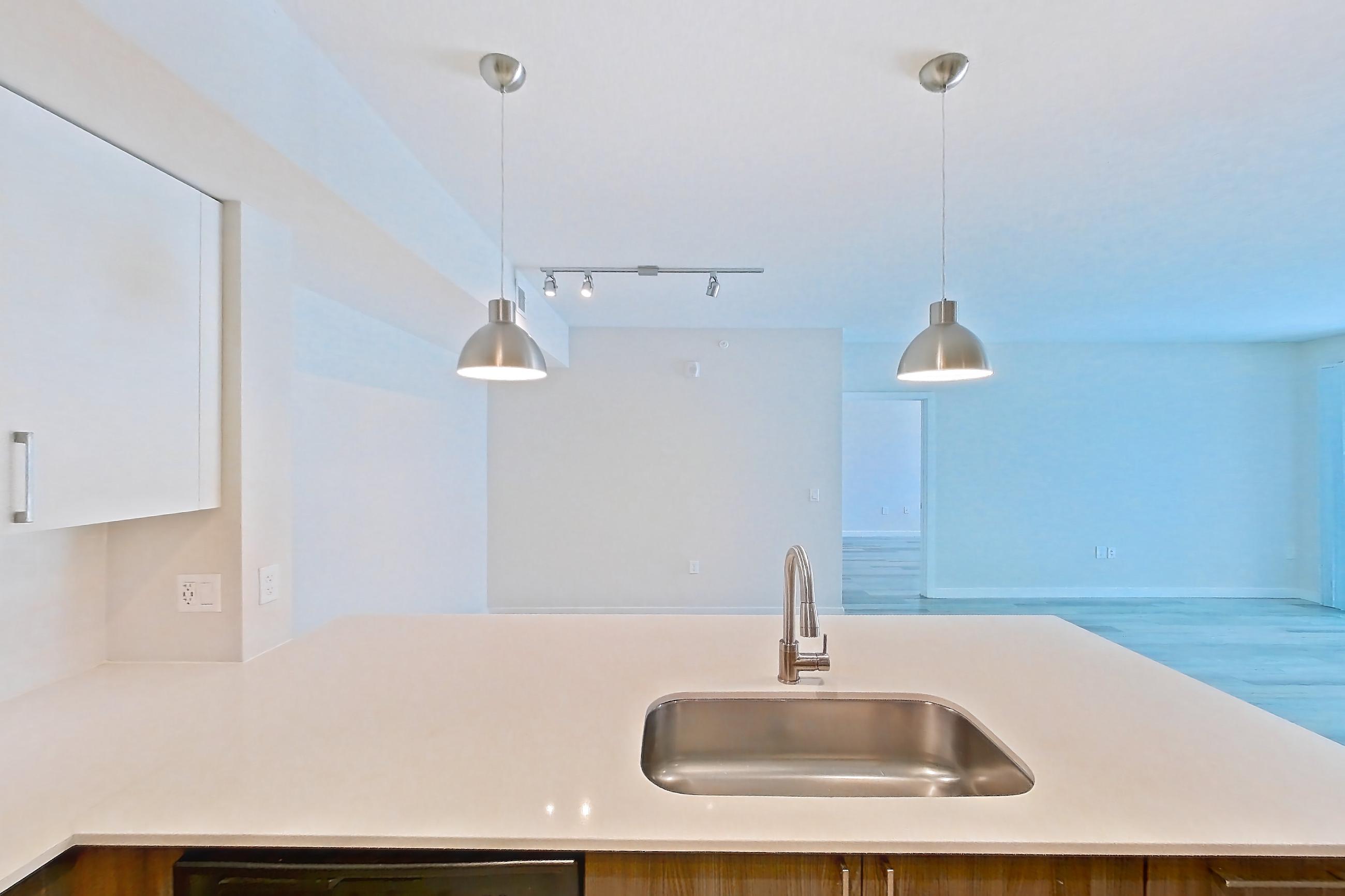 Kitchen with dishwasher, electric range, light countertops, light stone countertops, light wood-finish flooring, microwave, oven/range, refrigerator, and stainless steel appliances, Apartment 15-108 at Cortland South Kendall