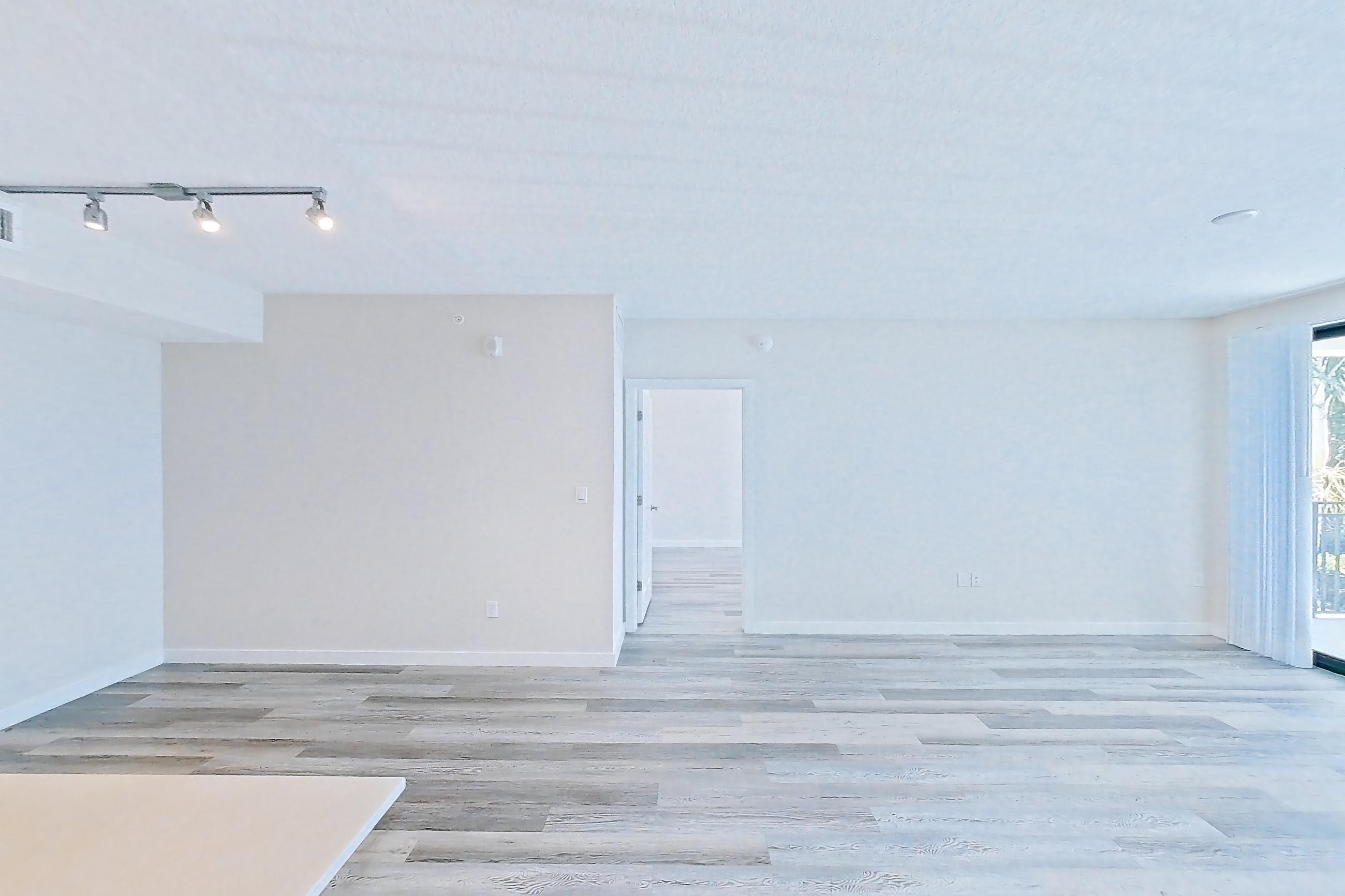 Kitchen entryway with electric range, light countertops, light stone countertops, light wood-finish flooring, oven/range, refrigerator, and stainless steel appliances, Apartment 17-205 at Cortland South Kendall