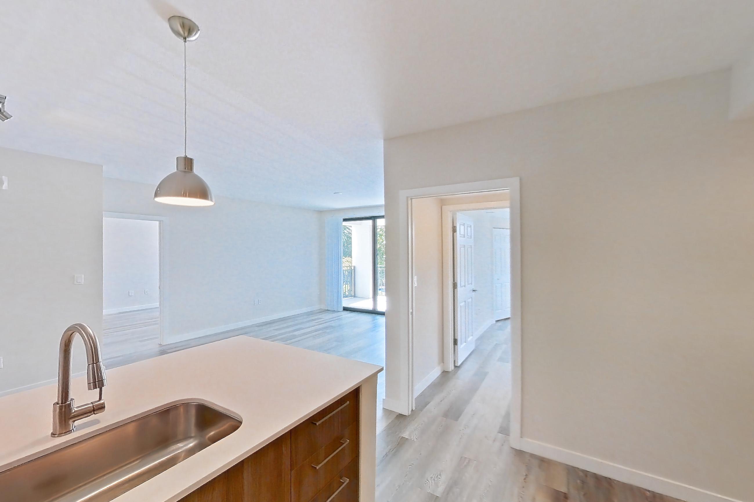 Kitchen with dishwasher, electric range, light countertops, light stone countertops, light wood-finish flooring, microwave, oven/range, refrigerator, and stainless steel appliances, Apartment 17-205 at Cortland South Kendall