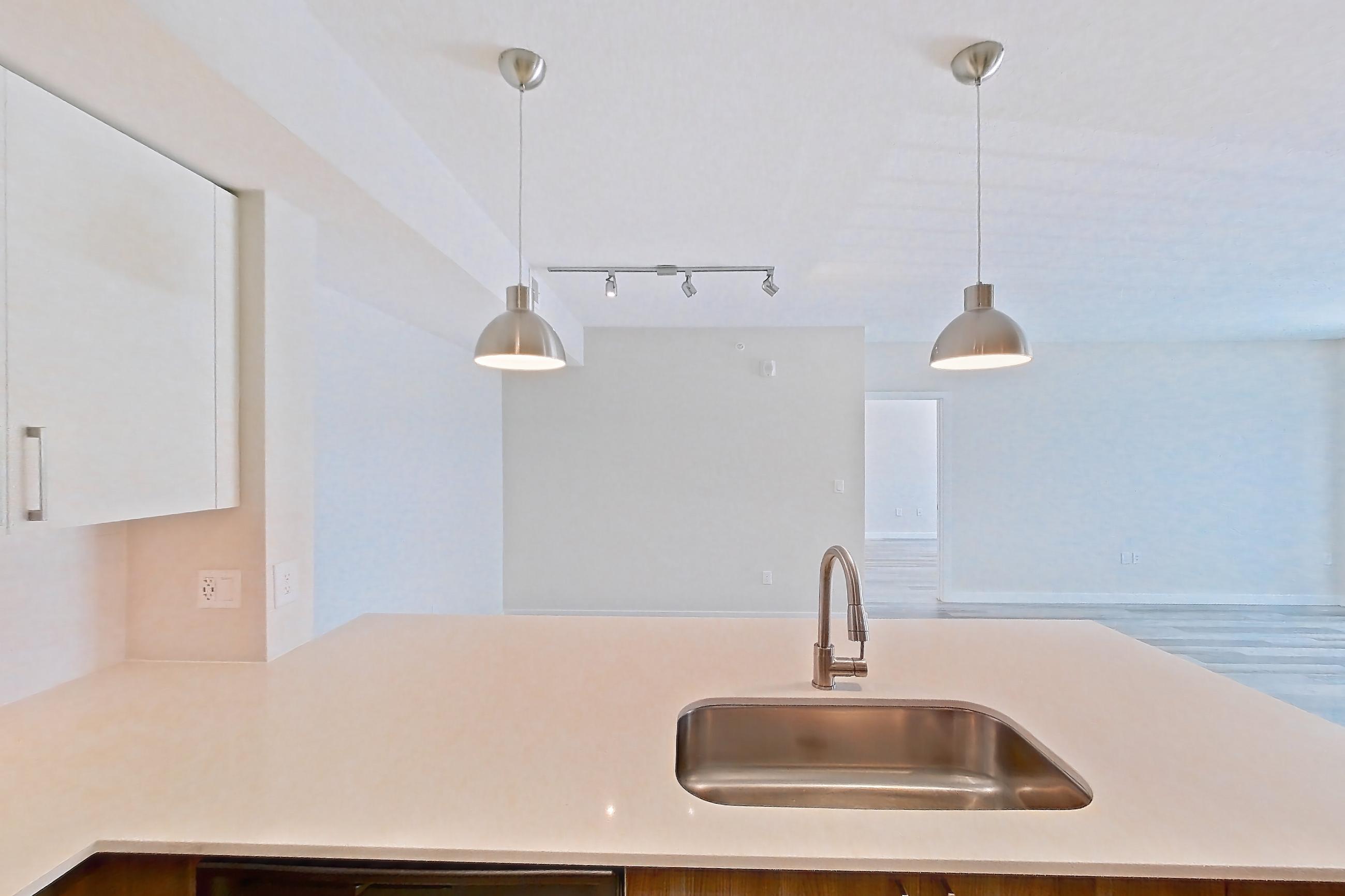 Kitchen with dishwasher, electric range, light countertops, light stone countertops, light wood-finish flooring, microwave, oven/range, refrigerator, and stainless steel appliances, Apartment 17-205 at Cortland South Kendall