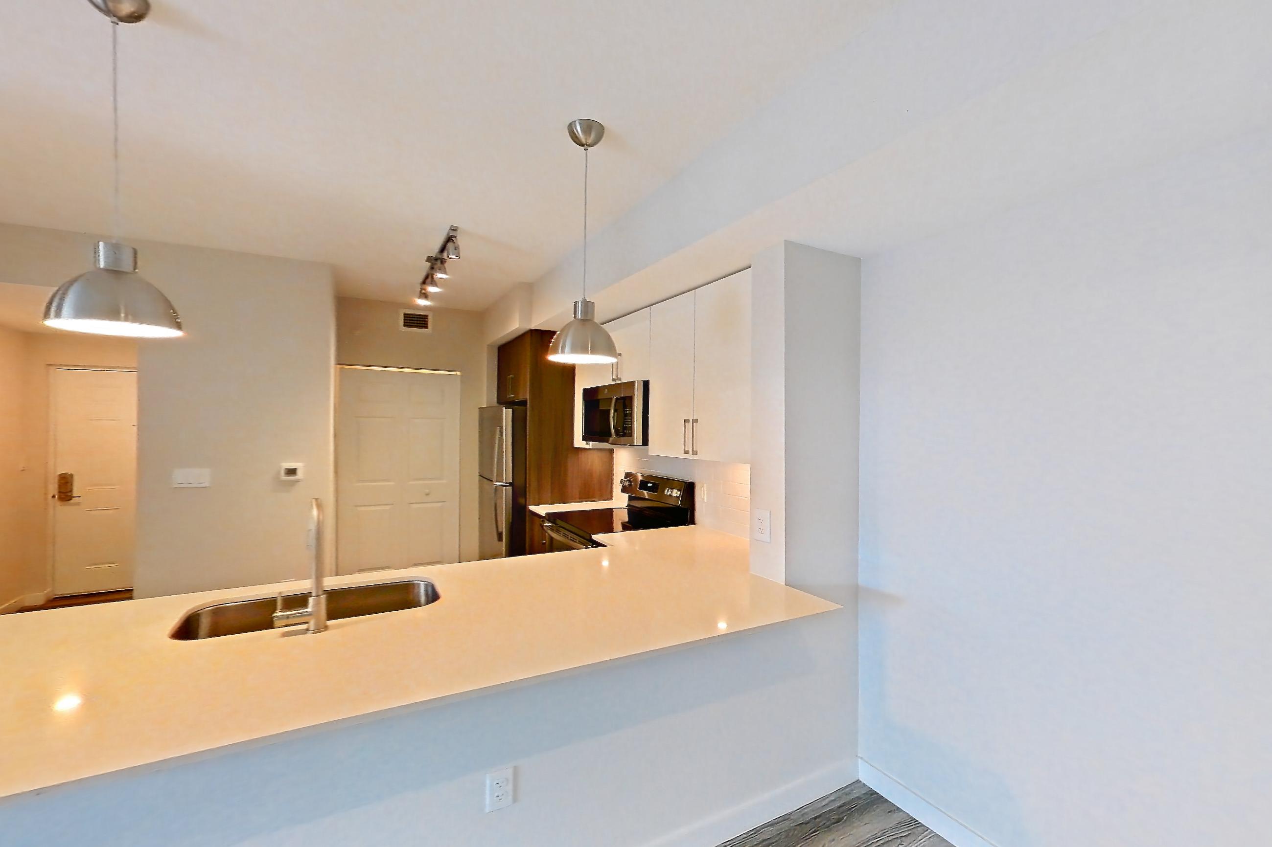 Living space with electric range, light stone countertops, light wood-finish flooring, oven/range, refrigerator, and stainless steel appliances, Apartment 17-205 at Cortland South Kendall
