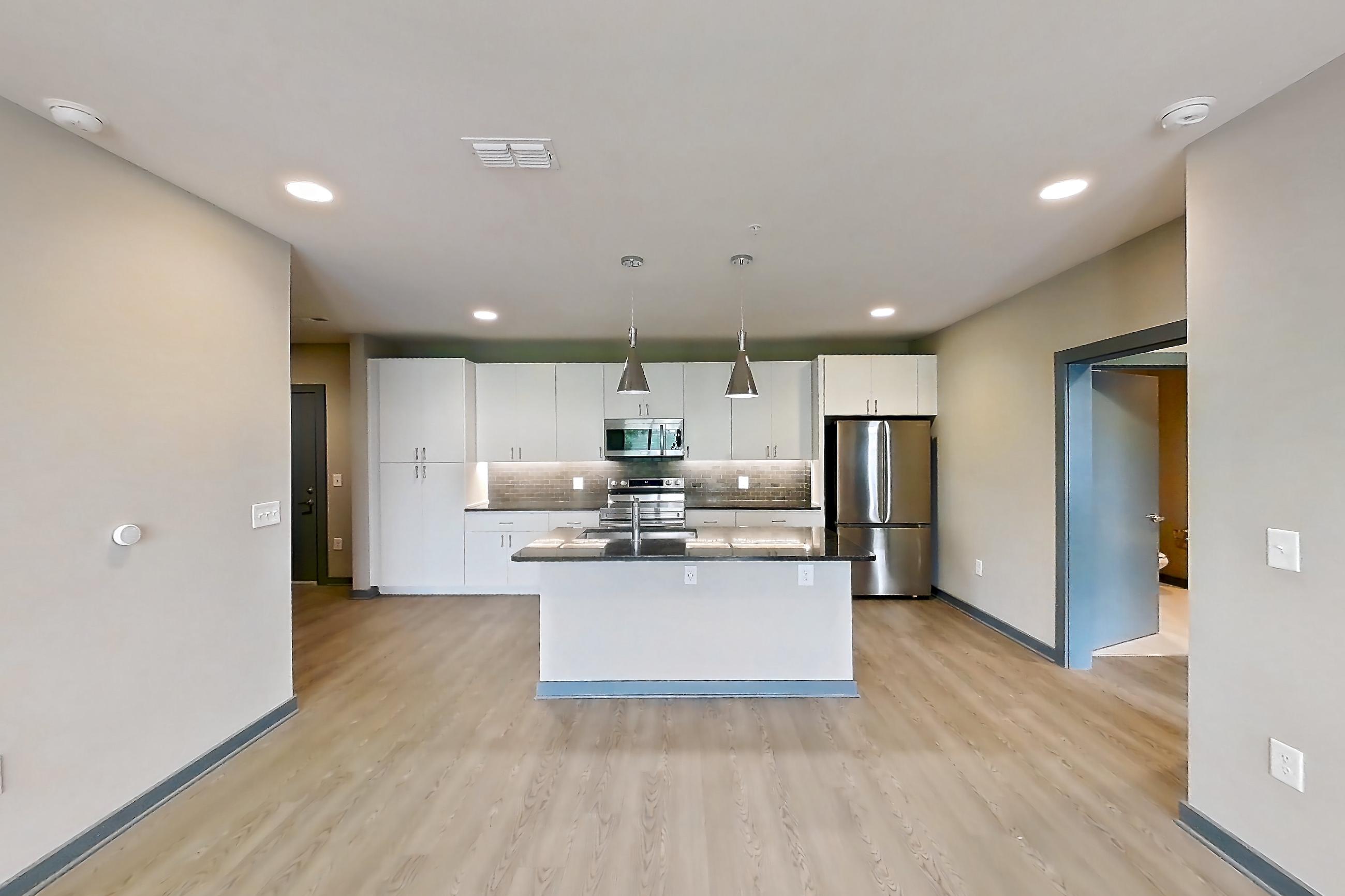 Living space with dark stone countertops, electric range, kitchen island, light wood-finish flooring, oven/range, refrigerator, and stainless steel appliances, Apartment 2040 at Cortland Westshore