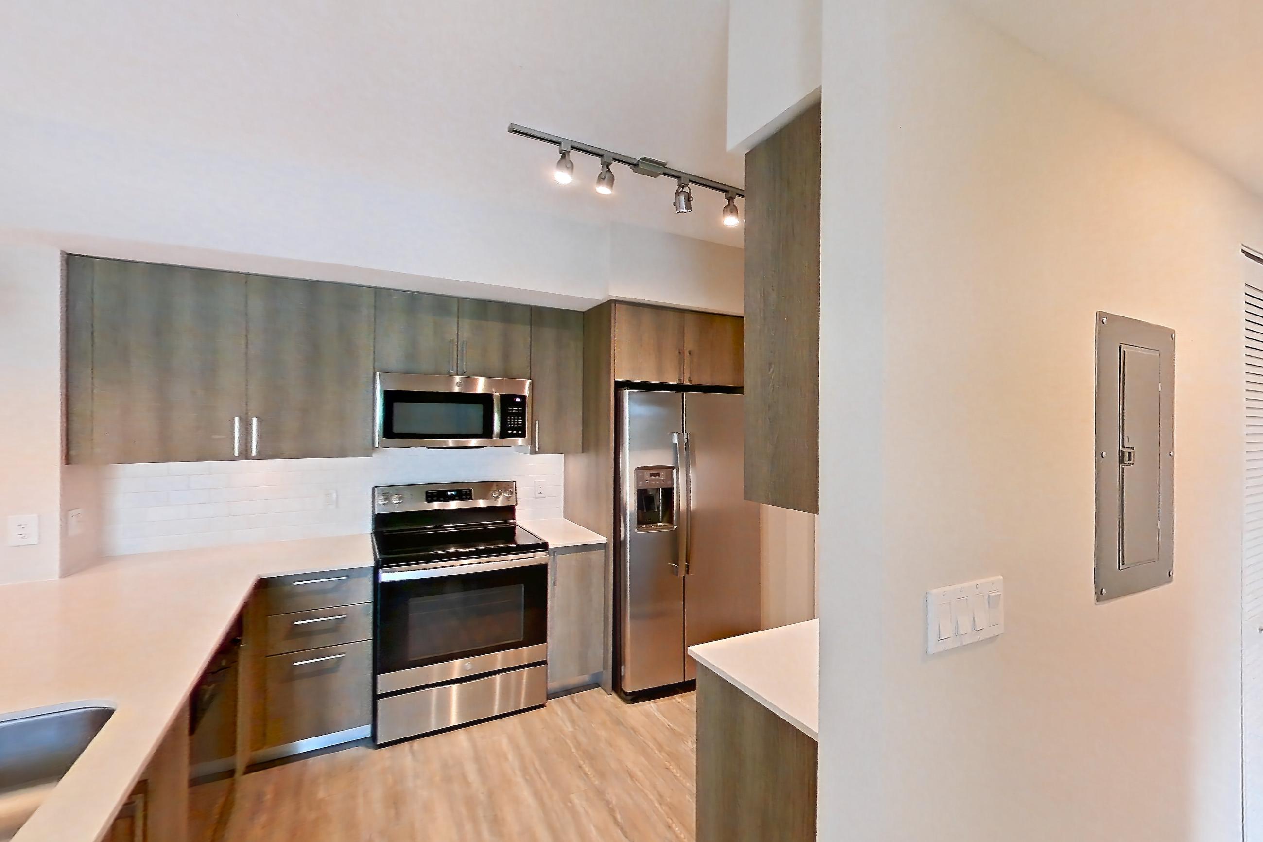 Kitchen entryway with electric range, light stone countertops, light wood-finish flooring, oven/range, range hood, refrigerator, stainless steel appliances, and water & ice dispenser, Apartment 08-301 at Cortland South Kendall