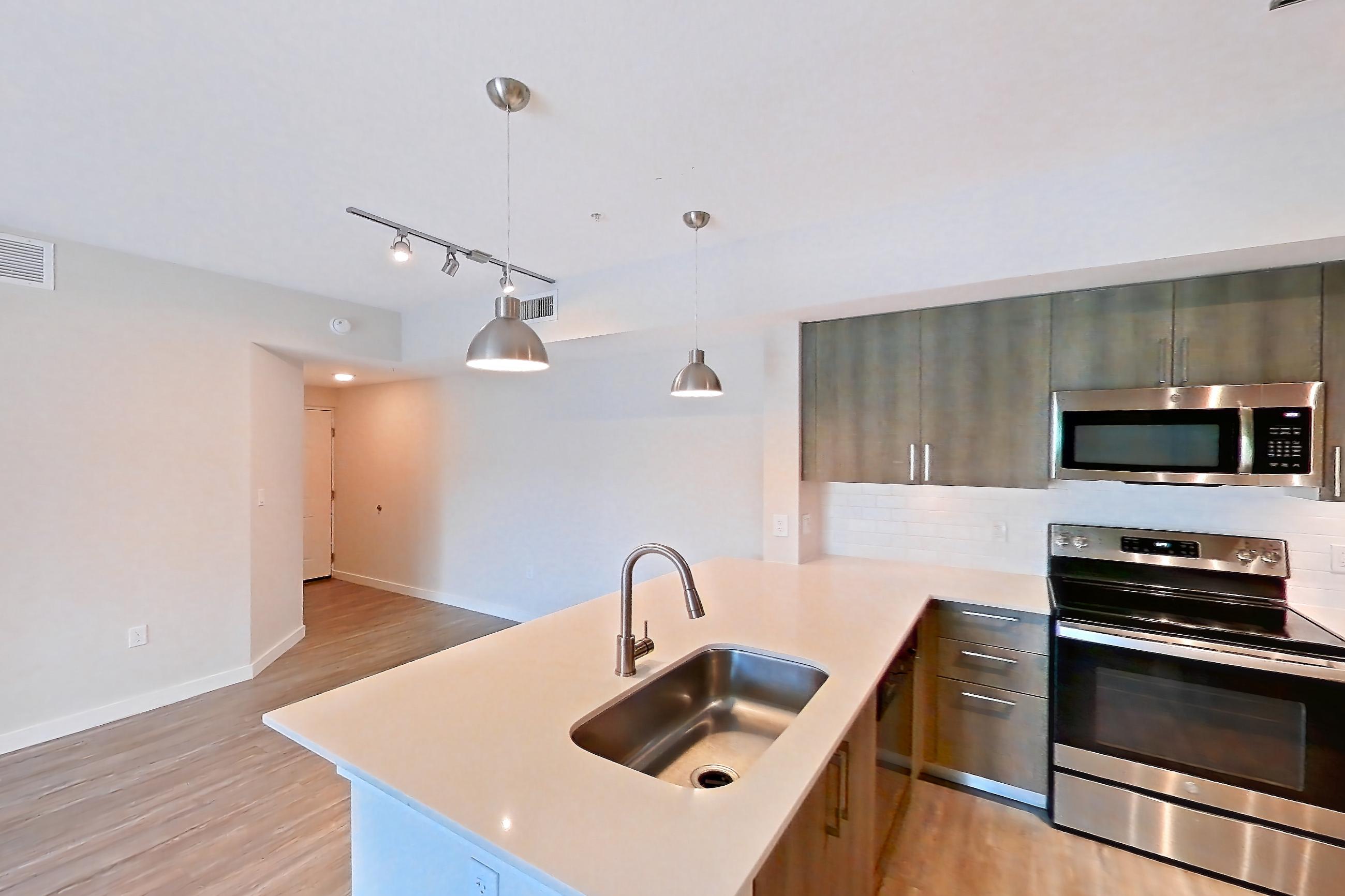 Kitchen entryway with electric range, light stone countertops, light wood-finish flooring, oven/range, range hood, refrigerator, stainless steel appliances, and water & ice dispenser, Apartment 08-301 at Cortland South Kendall