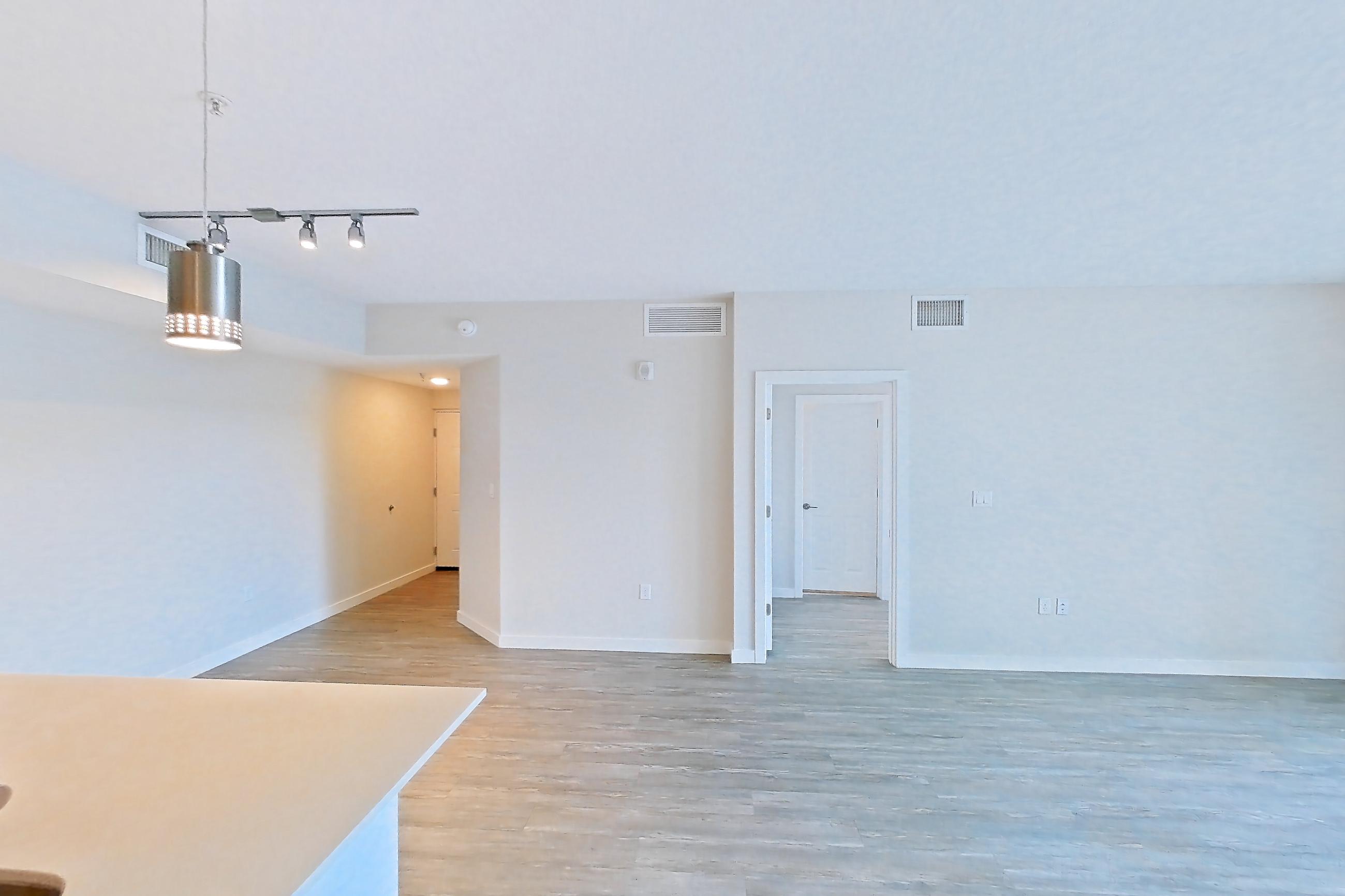 Kitchen entryway with electric range, light countertops, light stone countertops, light wood-finish flooring, oven/range, range hood, refrigerator, stainless steel appliances, and water & ice dispenser, Apartment 08-303 at Cortland South Kendall