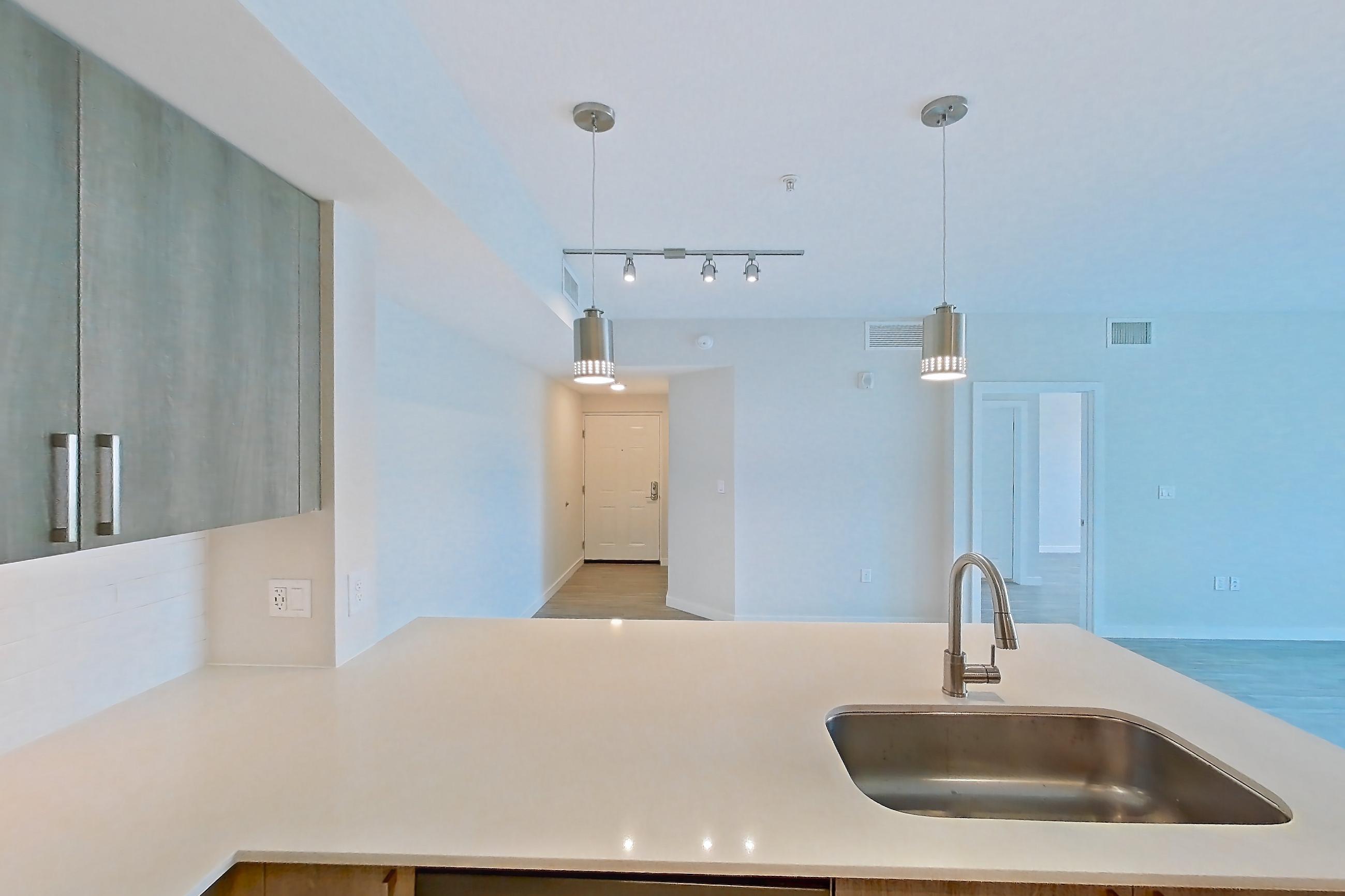 Kitchen with dishwasher, electric range, light countertops, light stone countertops, light wood-finish flooring, microwave, oven/range, refrigerator, and stainless steel appliances, Apartment 08-303 at Cortland South Kendall