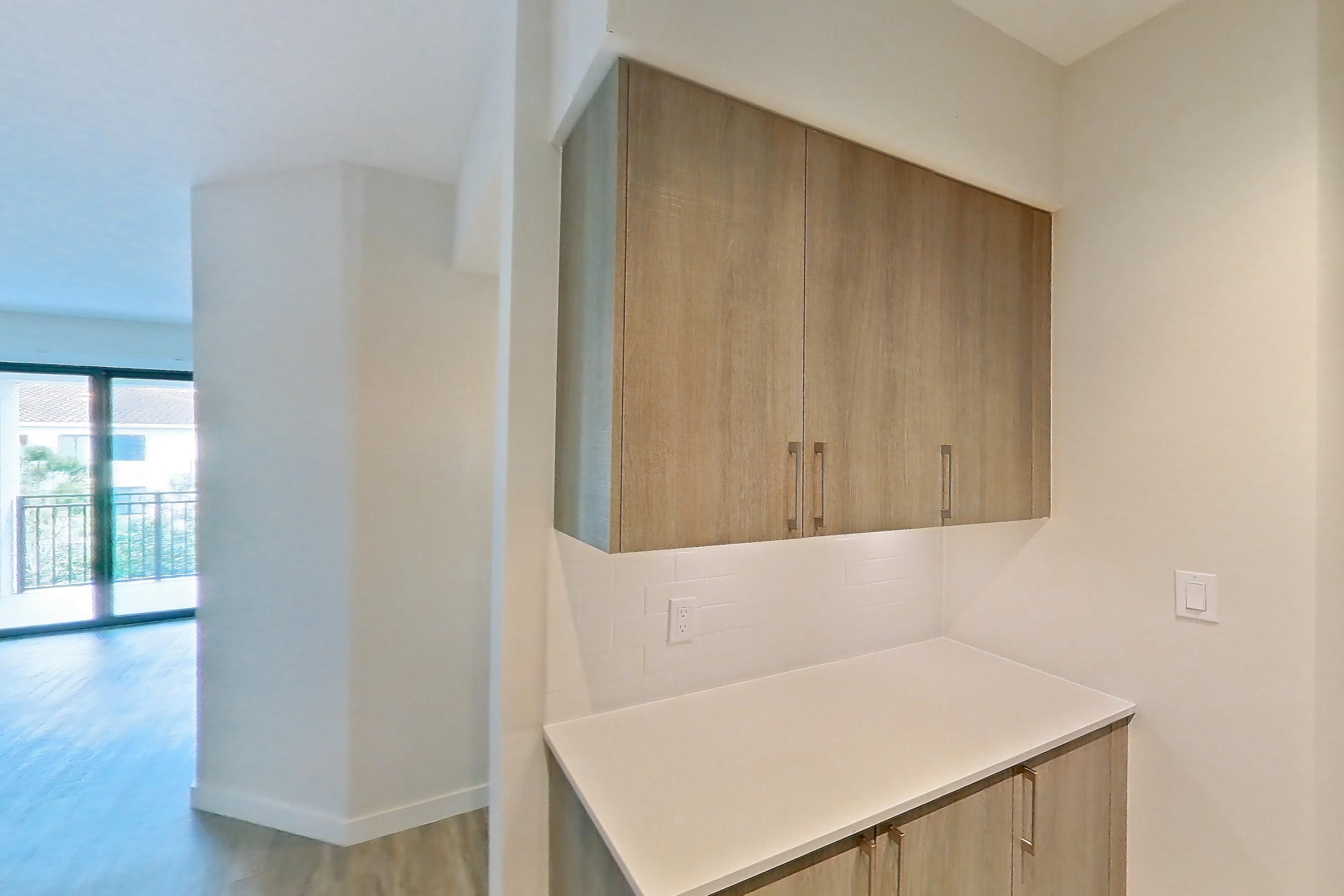 Kitchen with dishwasher, electric range, light countertops, light stone countertops, light wood-finish flooring, microwave, oven/range, refrigerator, and stainless steel appliances, Apartment 08-303 at Cortland South Kendall