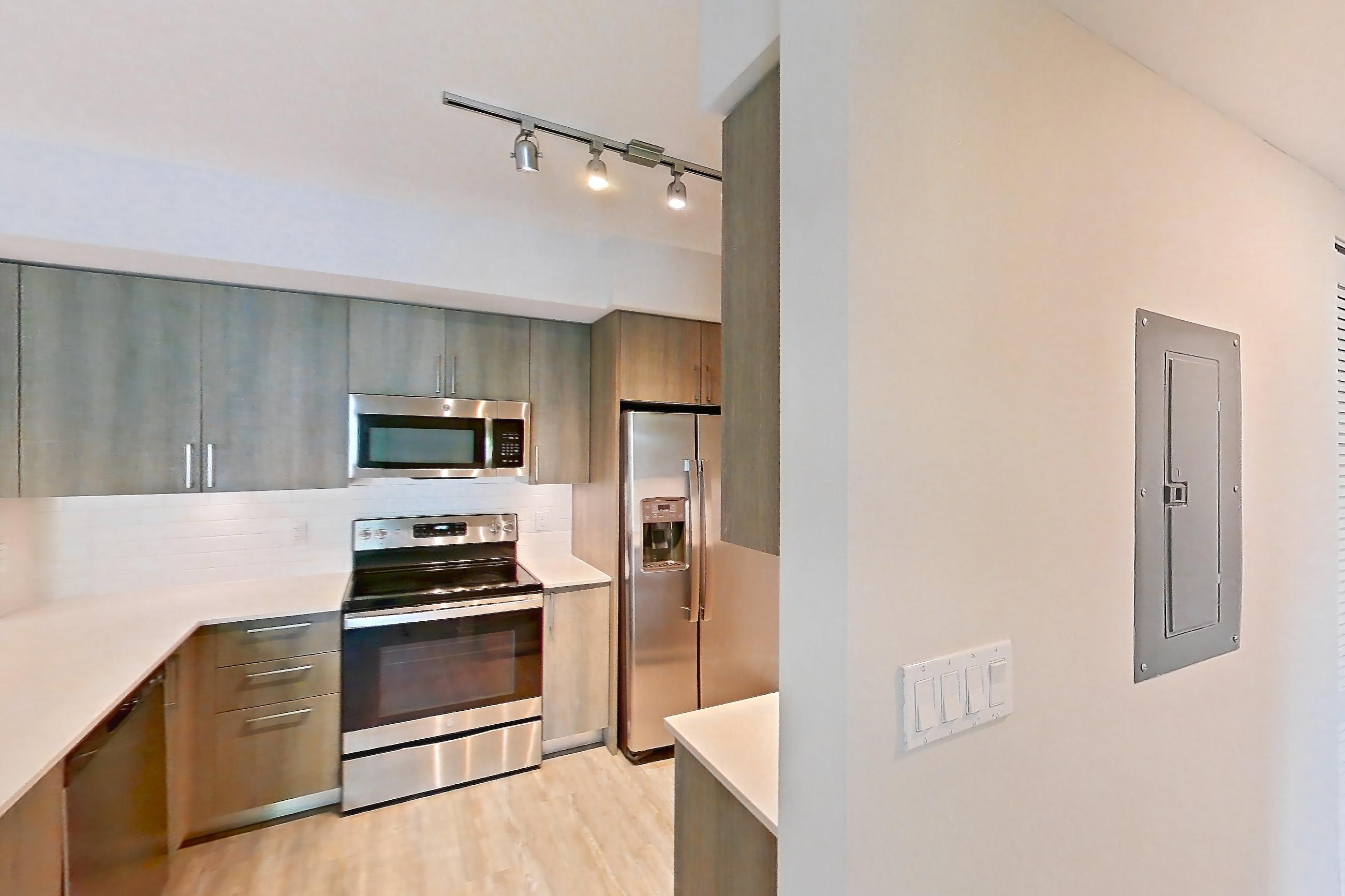 Kitchen entryway with dishwasher, electric range, light stone countertops, light wood-finish flooring, oven/range, refrigerator, stainless steel appliances, and water & ice dispenser, Apartment 08-201 at Cortland South Kendall