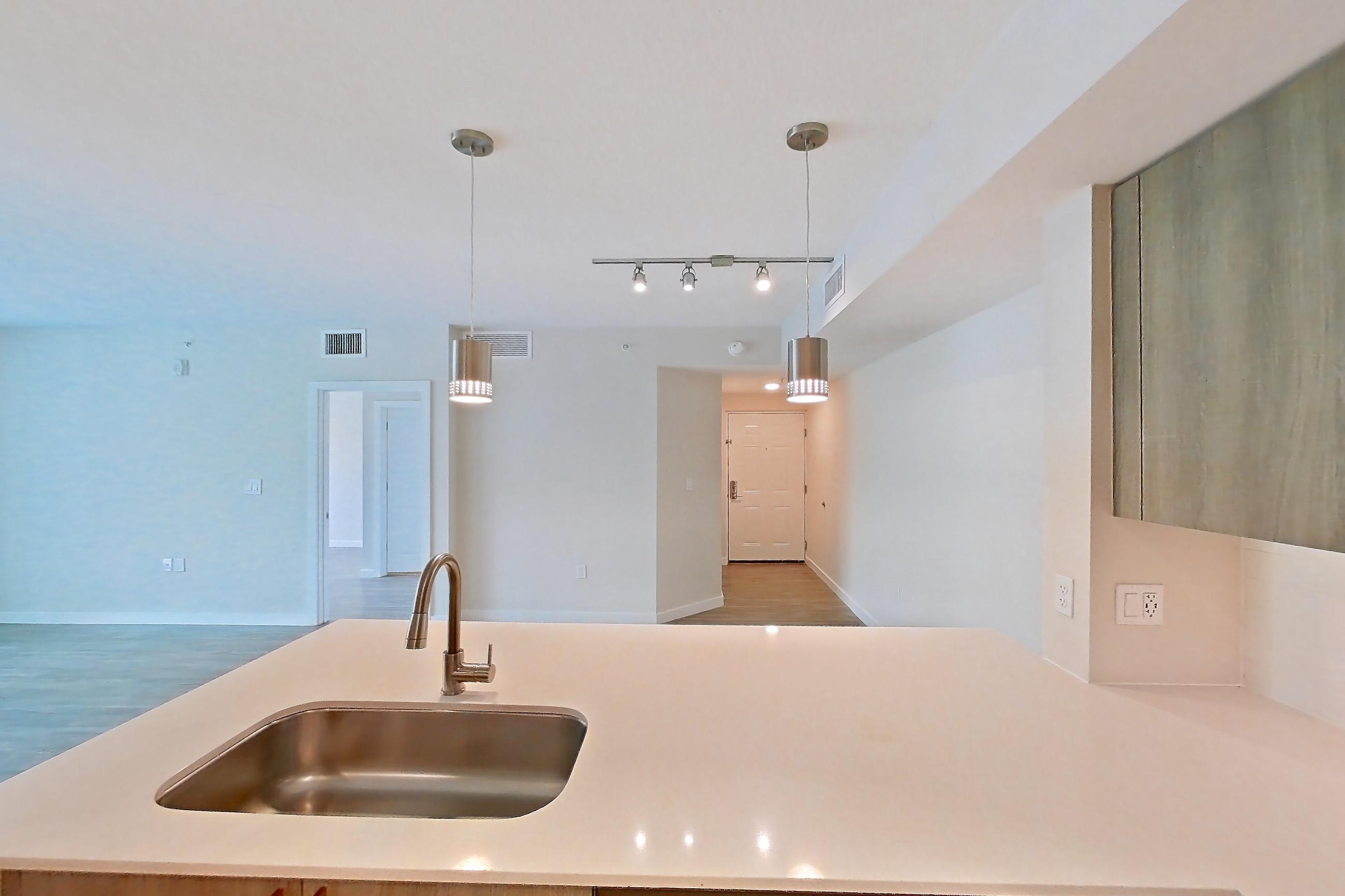 Kitchen with dishwasher, electric range, light countertops, light stone countertops, light wood-finish flooring, microwave, oven/range, and stainless steel appliances, Apartment 08-201 at Cortland South Kendall