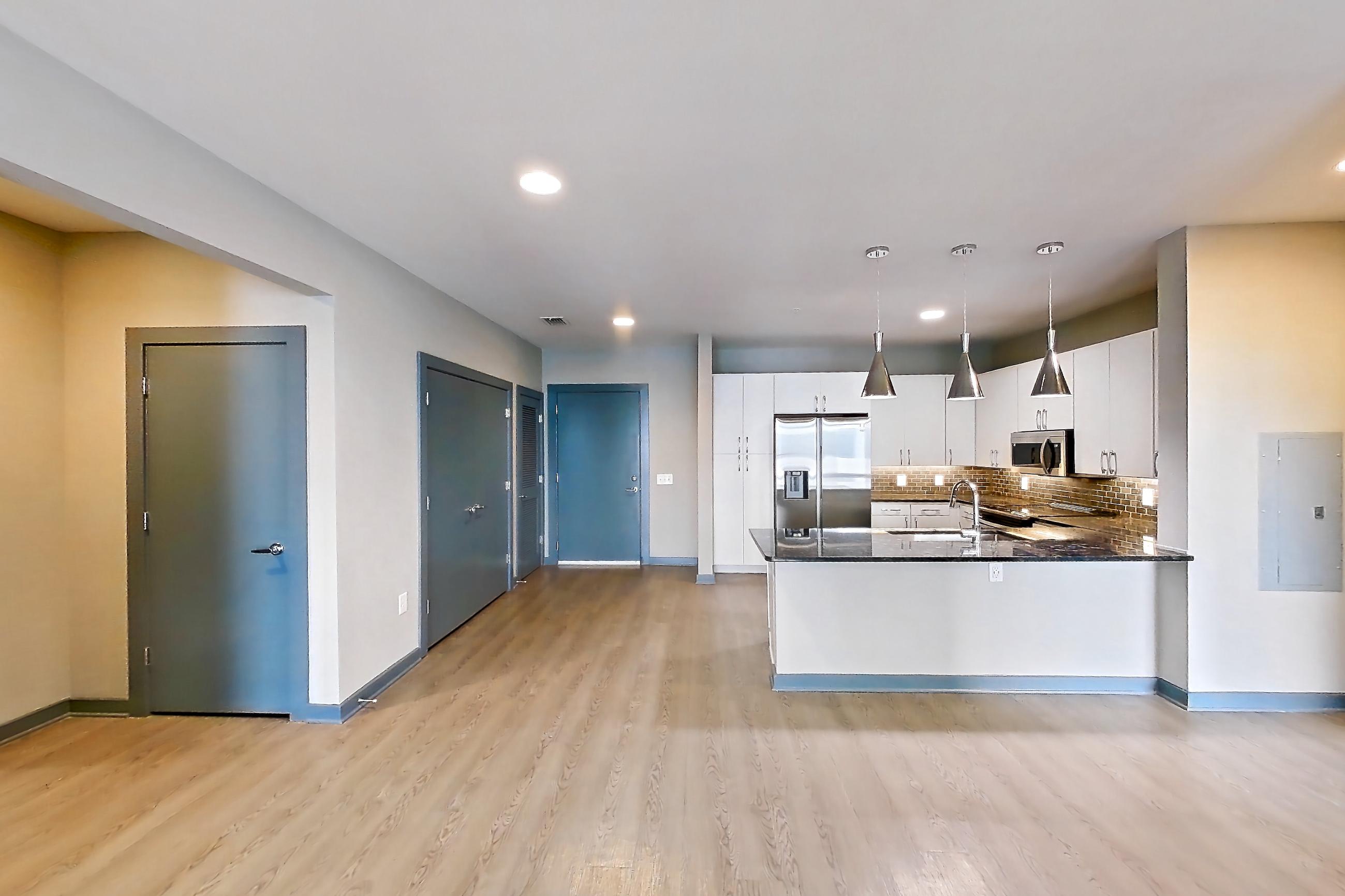 Living space with dark stone countertops, light wood-finish flooring, refrigerator, and stainless steel appliances, Apartment 6017 at Cortland Westshore