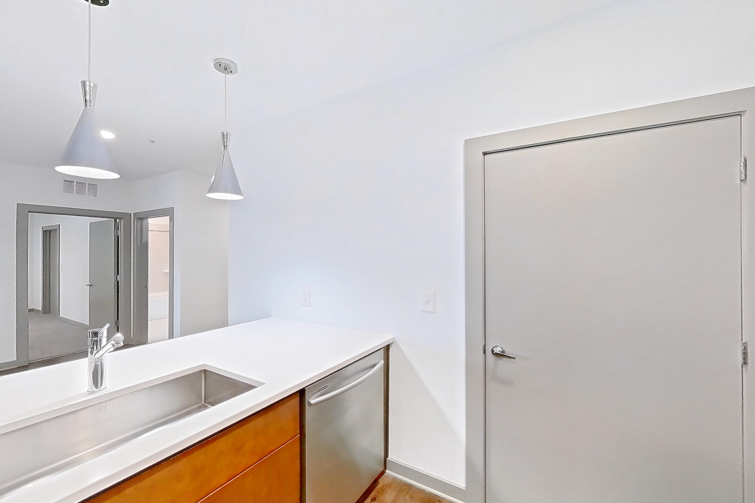Kitchen with dark wood-finish flooring, dishwasher, electric range, light countertops, light wood-finish flooring, microwave, oven/range, refrigerator, and stainless steel appliances, Apartment 1015 at Cortland Westshore