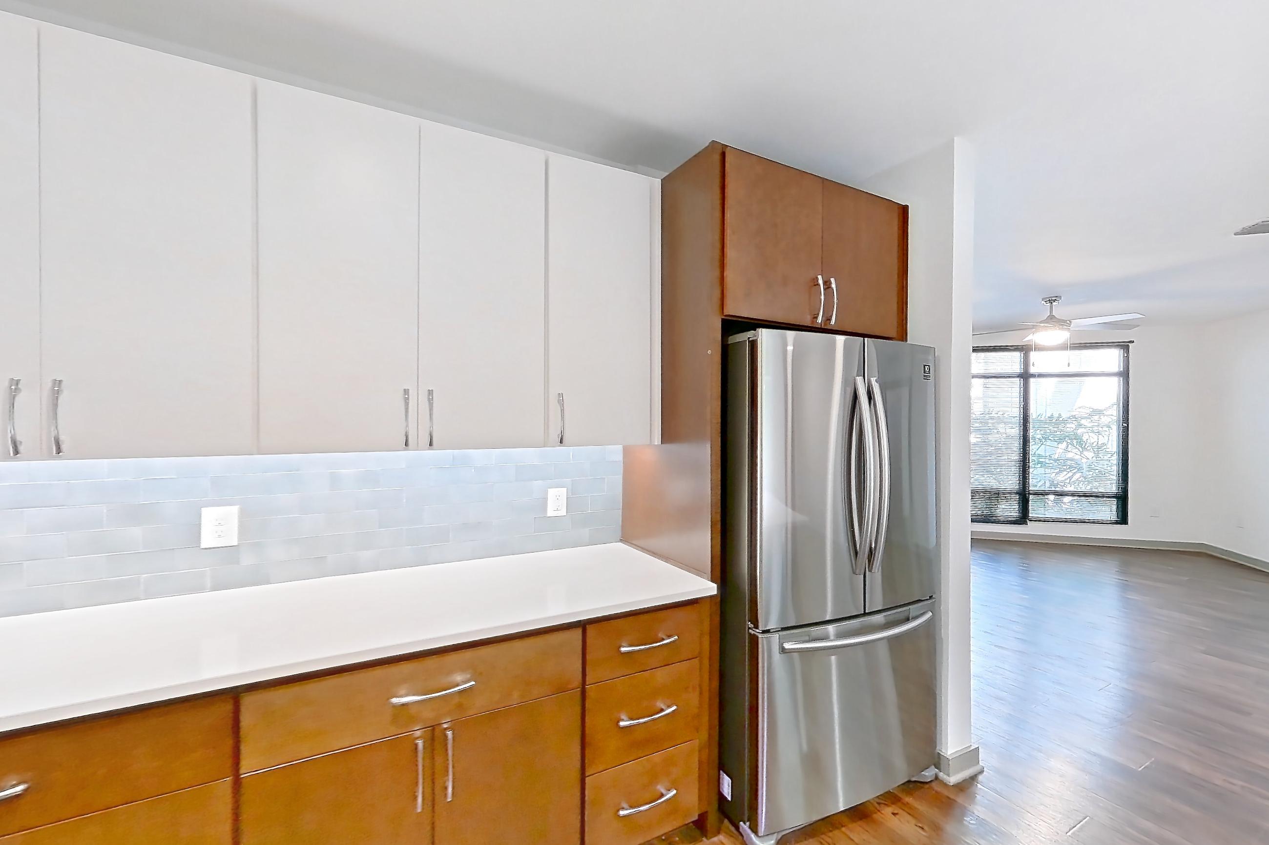 Kitchen with dark wood-finish flooring, dishwasher, electric range, light countertops, light wood-finish flooring, microwave, oven/range, refrigerator, and stainless steel appliances, Apartment 1015 at Cortland Westshore