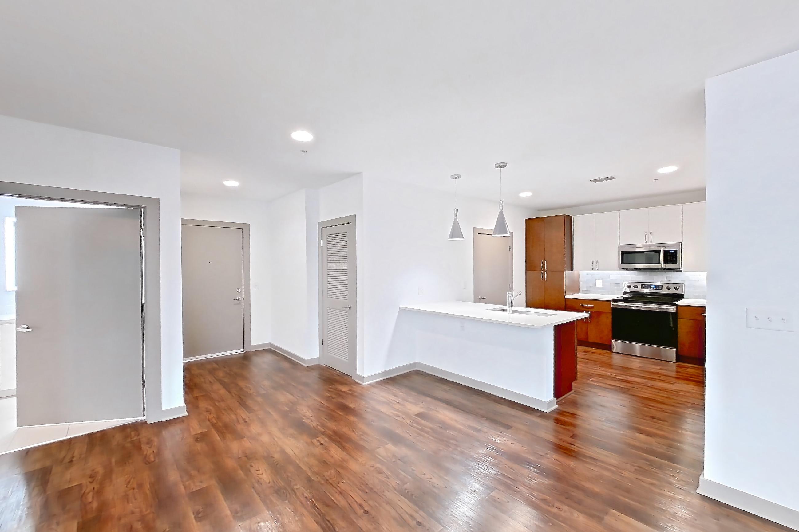 Living space with dark wood-finish flooring, electric range, light countertops, light stone countertops, oven/range, and stainless steel appliances, Apartment 1015 at Cortland Westshore