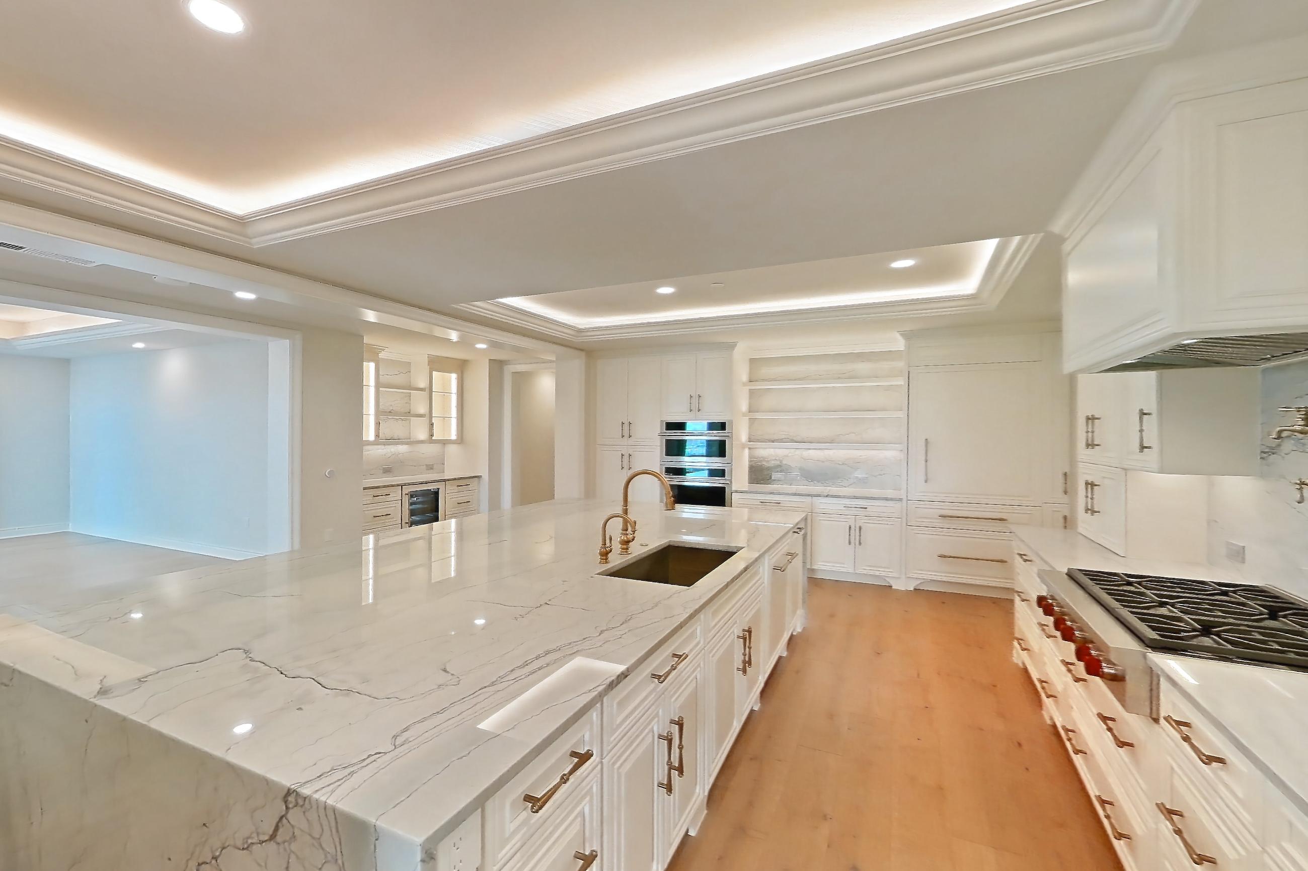 Kitchen space 2 with cooktop, gas cooktop, kitchen island, light stone countertops, light wood-finish flooring, oven/range, stainless steel appliances, and wood-finish flooring, Apartment 1807 at The Langley